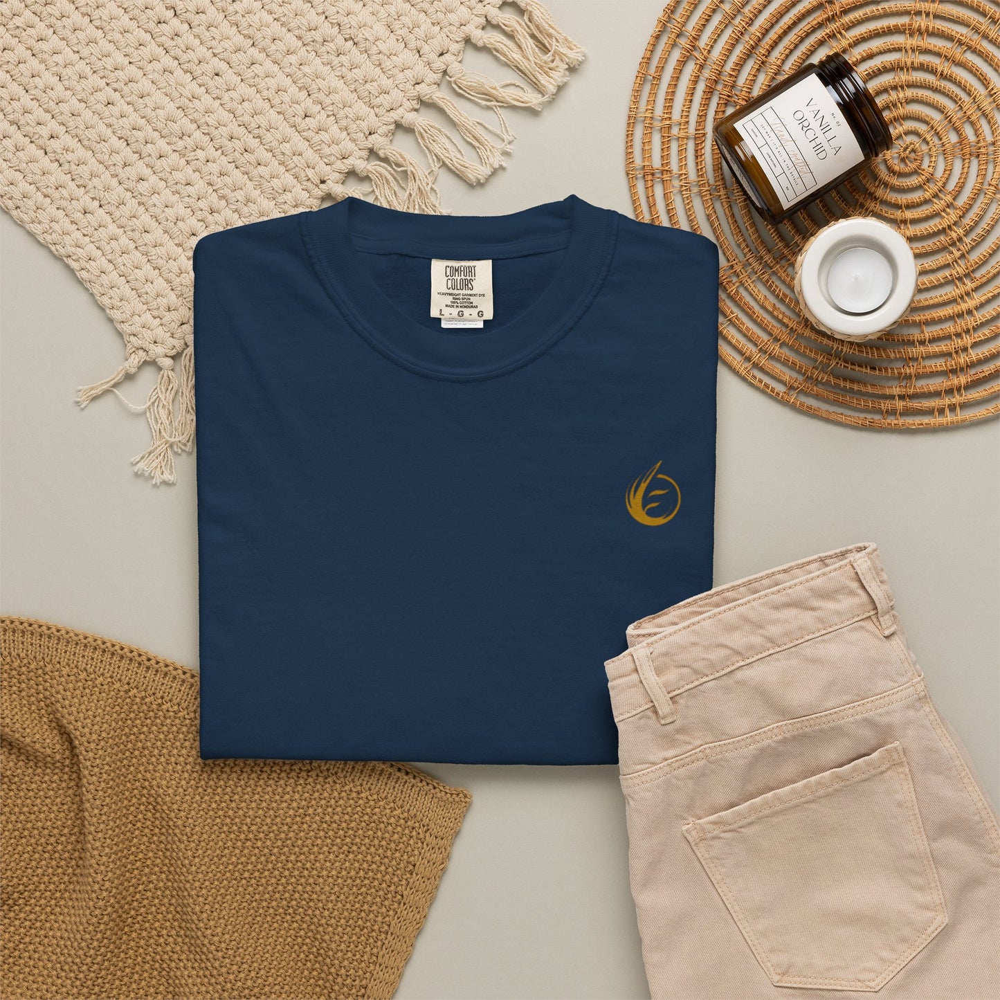 Navy blue t-shirt with 'EssenceInnoCreate' embroidery on a neutral surface with beige pants and decorative items.