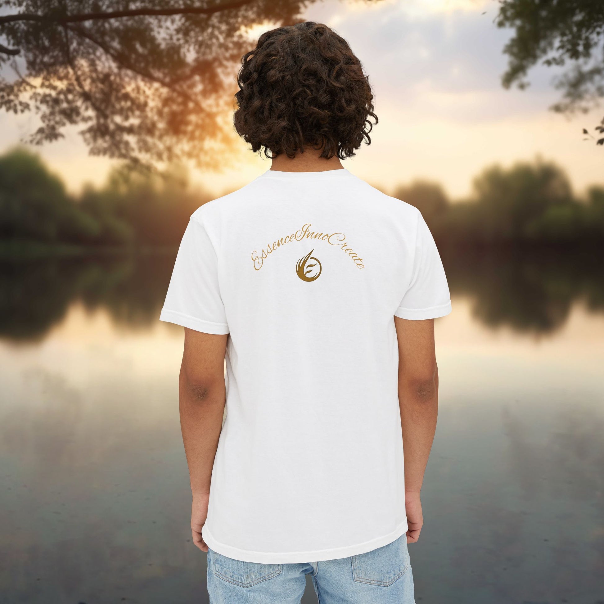 Person wearing a white t-shirt with 'EssenceInnoCreate' logo standing by a lake at sunset.