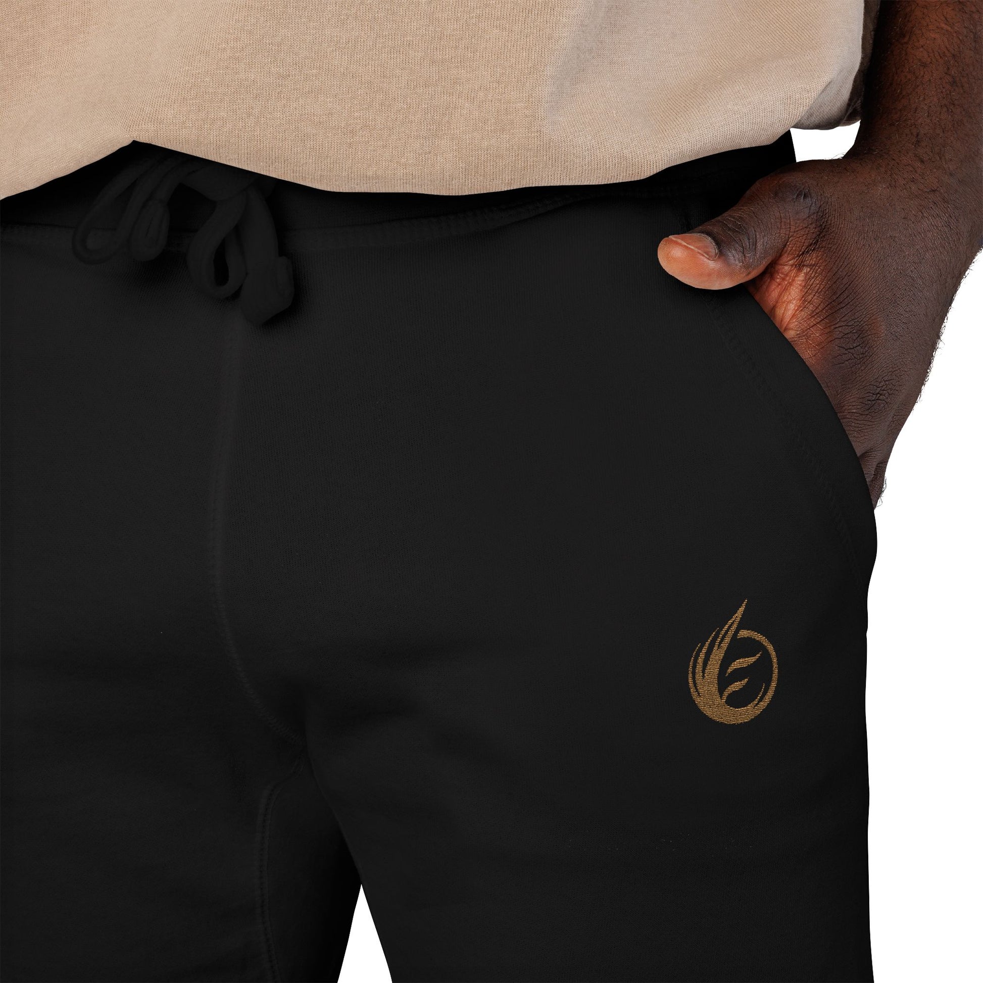 Black 'EssenceInnoCreate' Quiet Resolve sweatpants with a gold logo on a person wearing a beige shirt.
