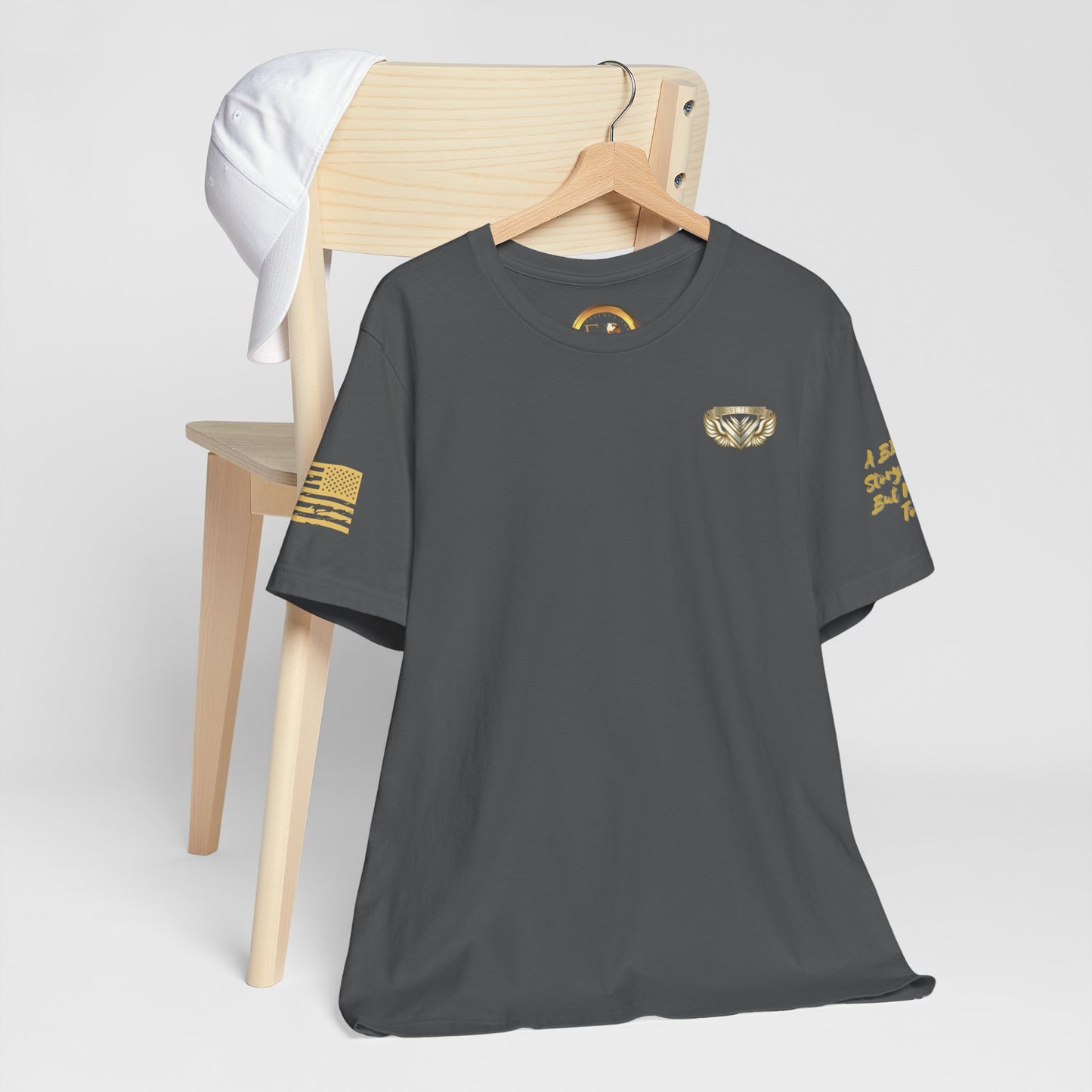Gray t-shirt with gold logos on a wooden chair against a white background