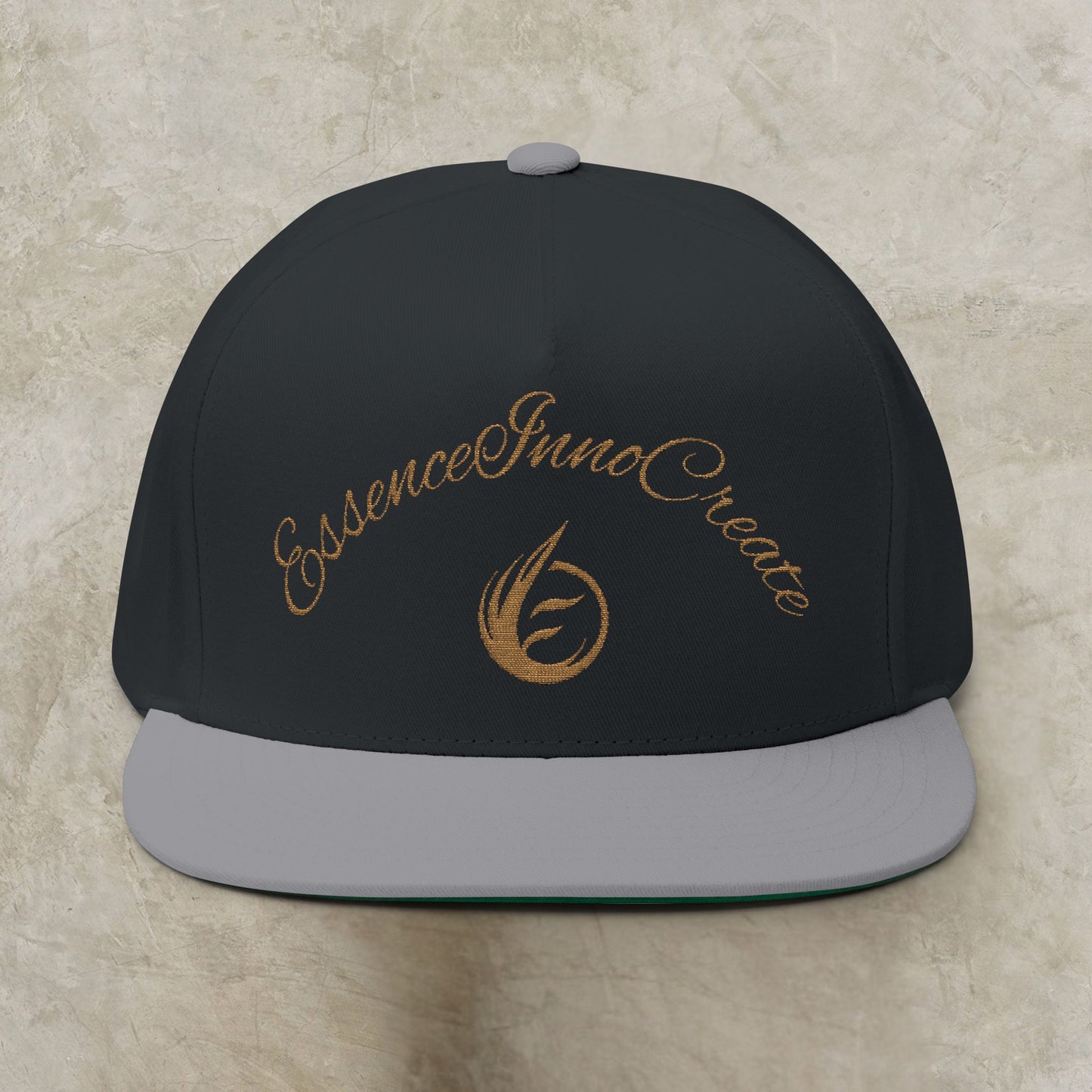 Black cap with gold EssenceInnoCreate text and logo on a beige background