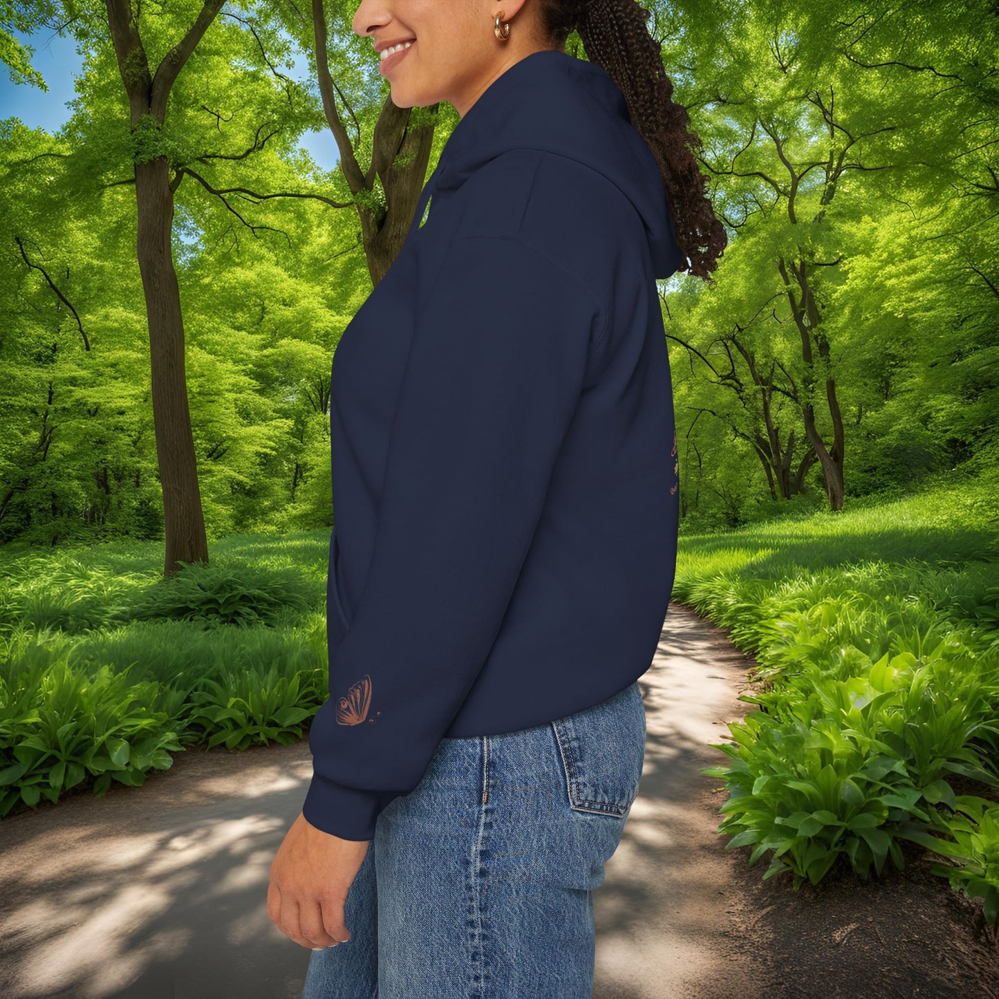 Person wearing a navy blue Essence Innovation Bohemian Butterfly Crest hoodie with a logo in a park setting