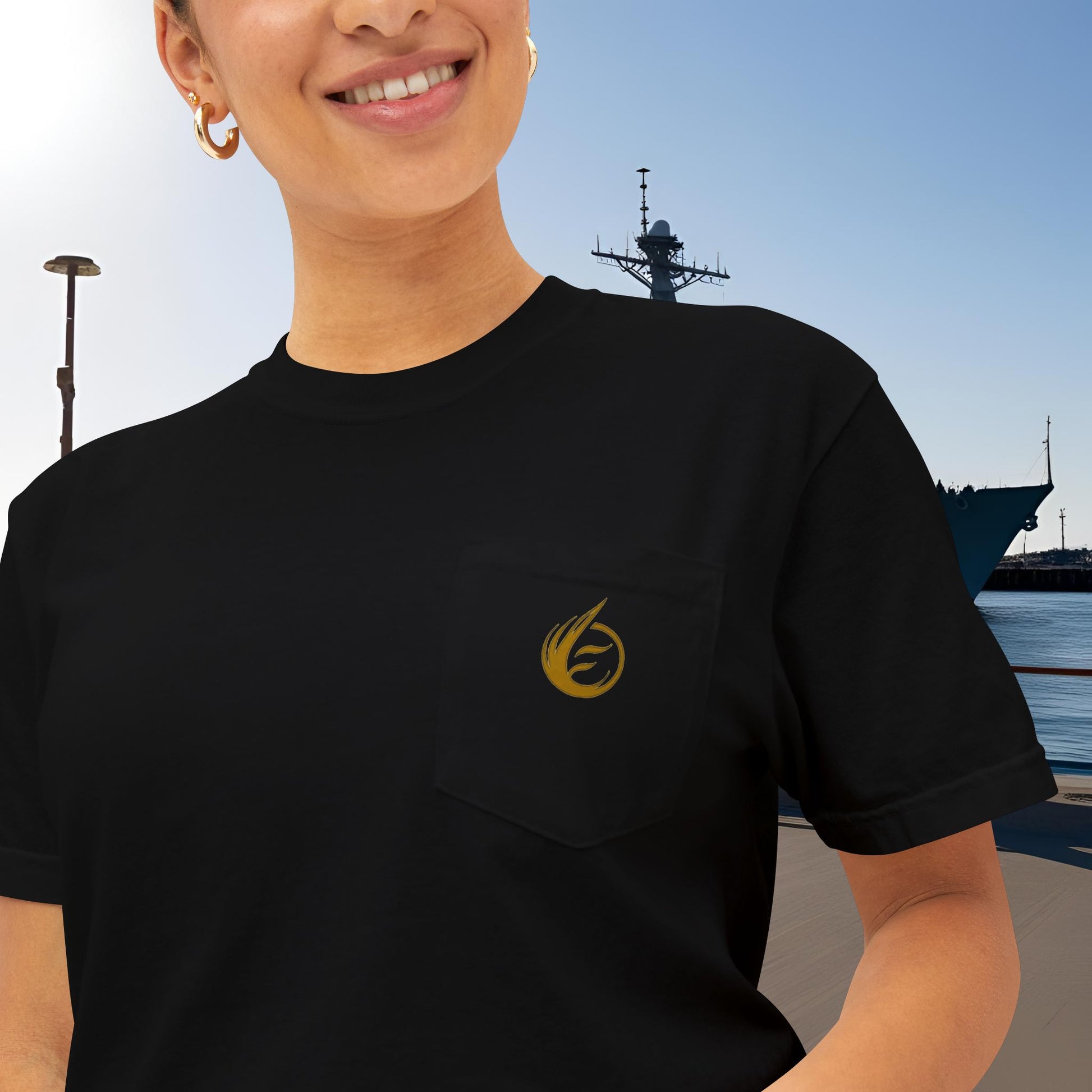 Person wearing a black t-shirt with 'EssenceInnoCreate' yellow logo, standing in front of a ship.