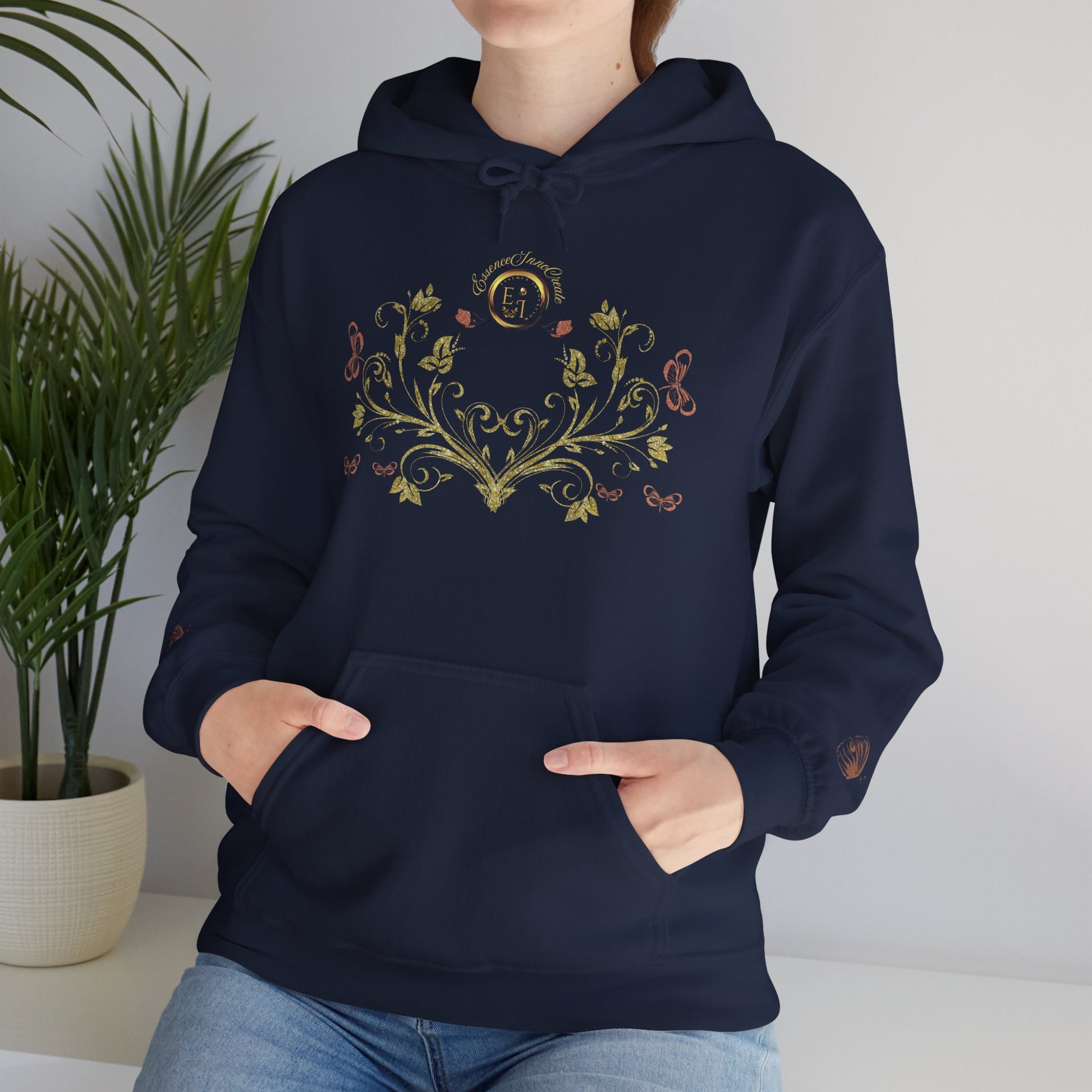 Person wearing a brown Essence Innovation Bohemian Butterfly Crest hoodie with a plant in the background