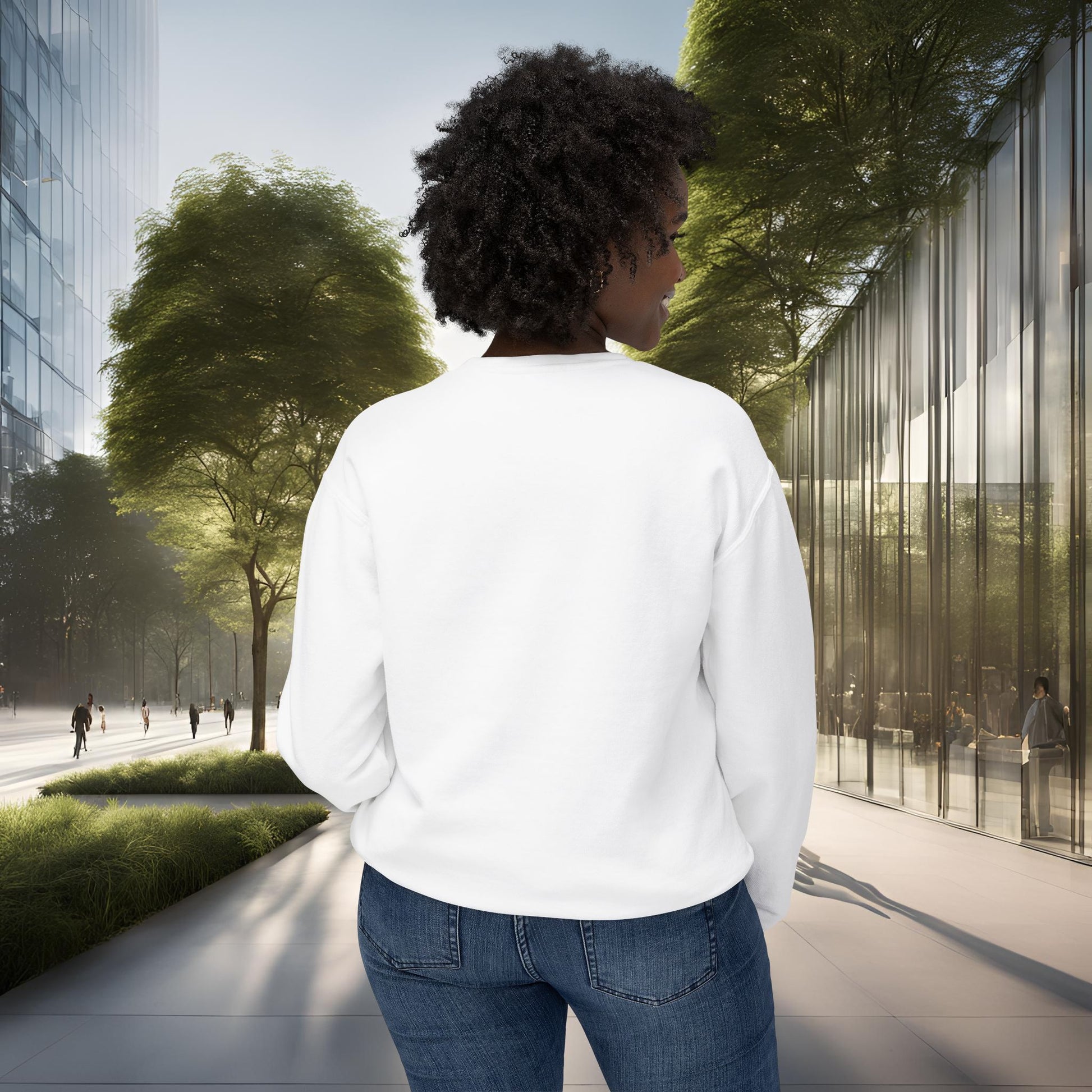 Person in a white shirt and blue jeans walking on a city street with modern buildings and trees.