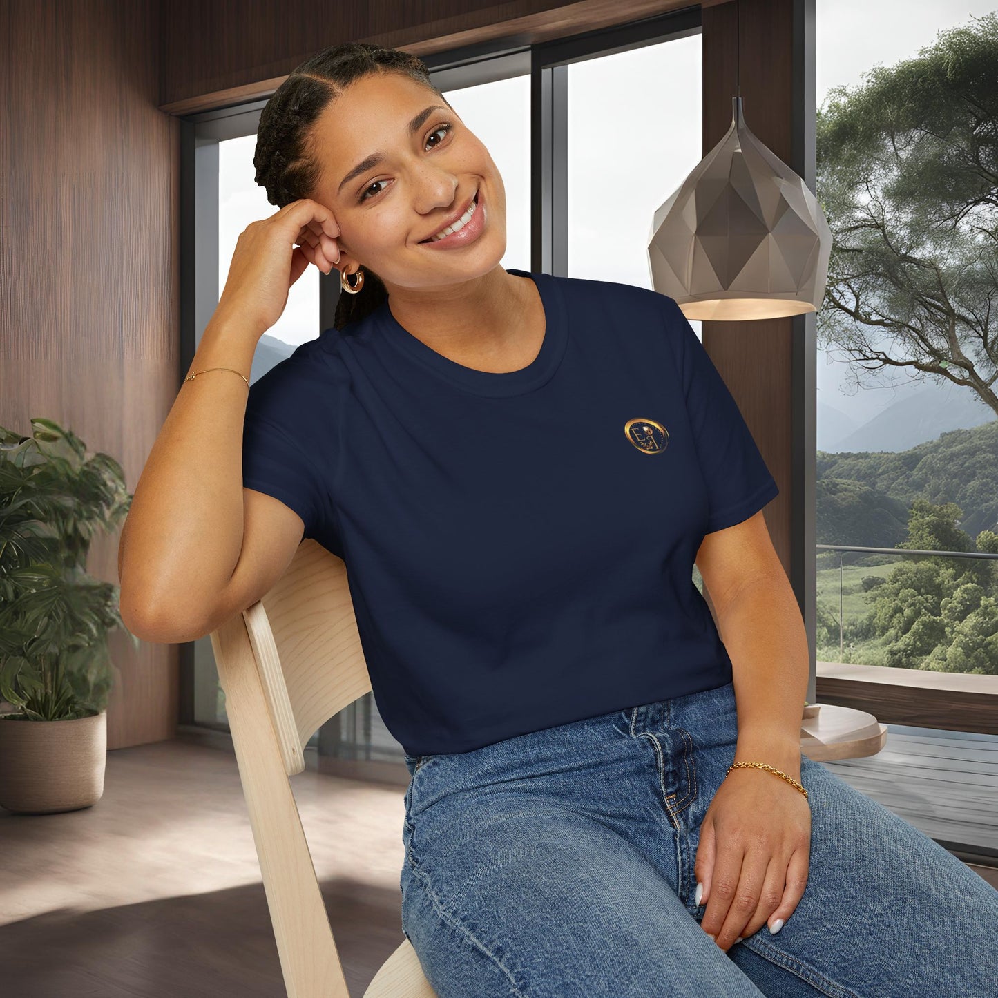 Woman wearing a navy t-shirt with an Essence Innovation logo, sitting indoors with a scenic view outside.
