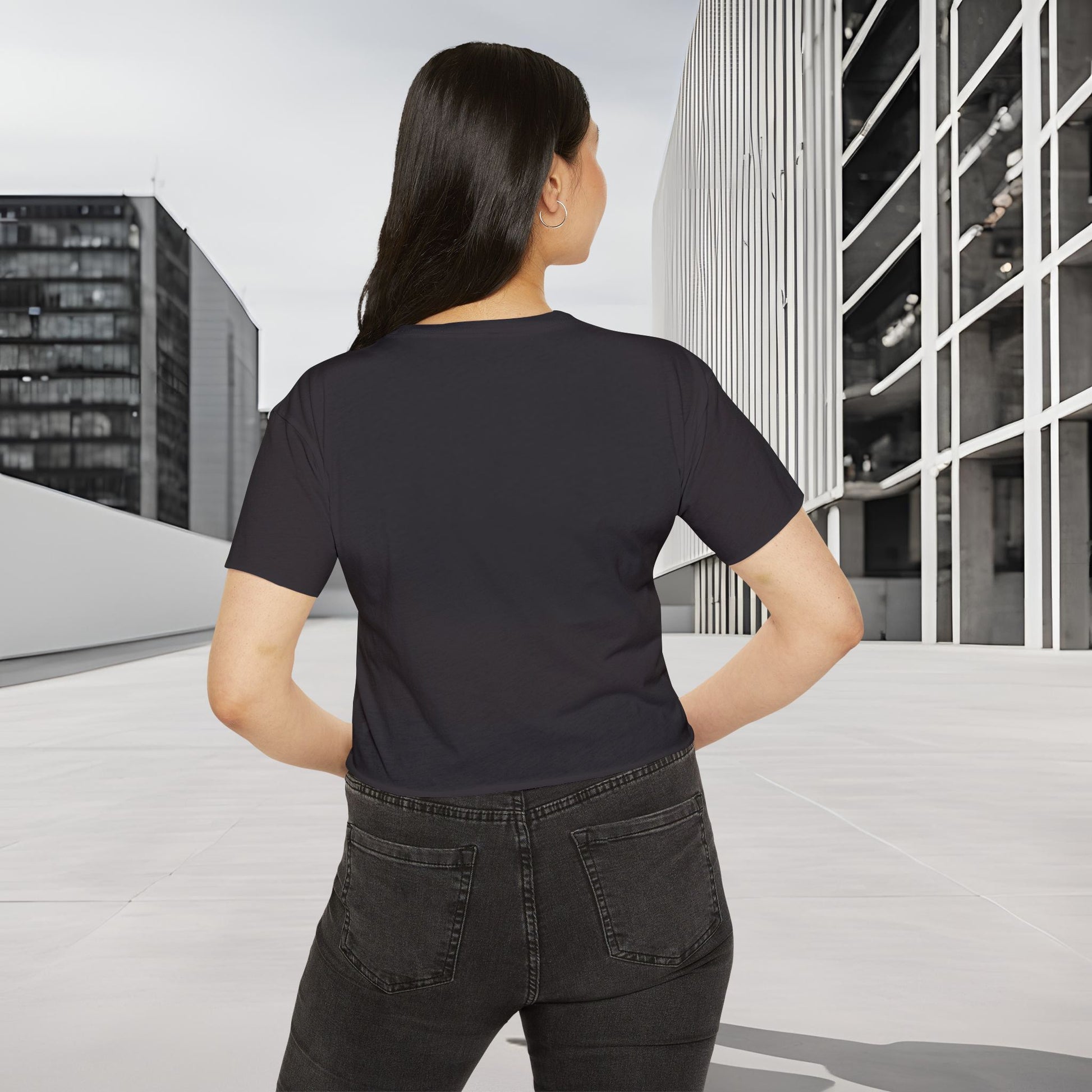 Person wearing a Essence Innovation Bohemian Butterfly black t-shirt and jeans standing in an urban setting with modern buildings.