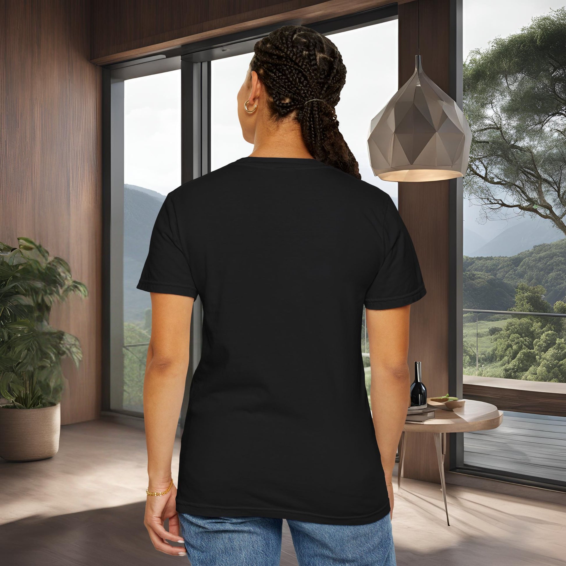 Person wearing a black 'EssenceInnoCreate' t-shirt in a modern room with large windows and a view of trees.