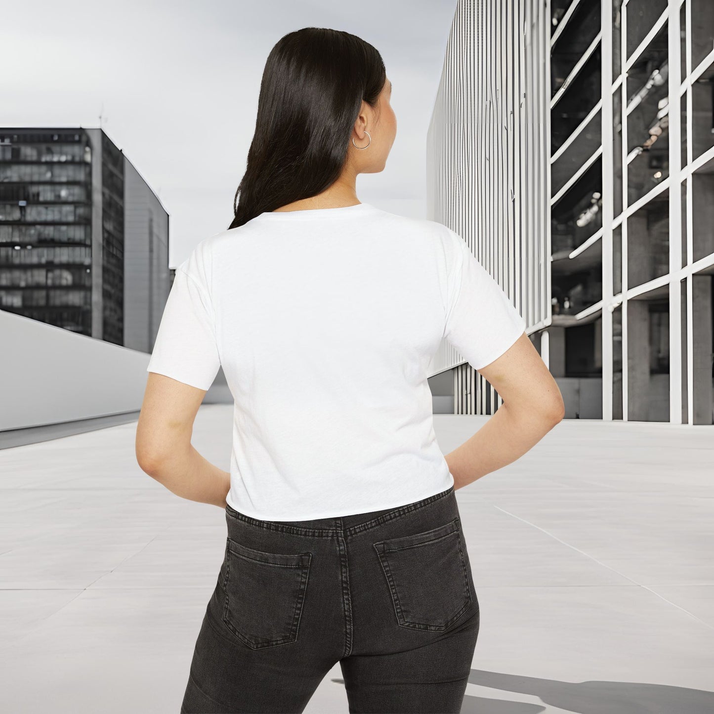 Person wearing a plain white Essence Innovation 'Design Meets Soul' t-shirt and black pants standing in an urban setting with modern buildings.