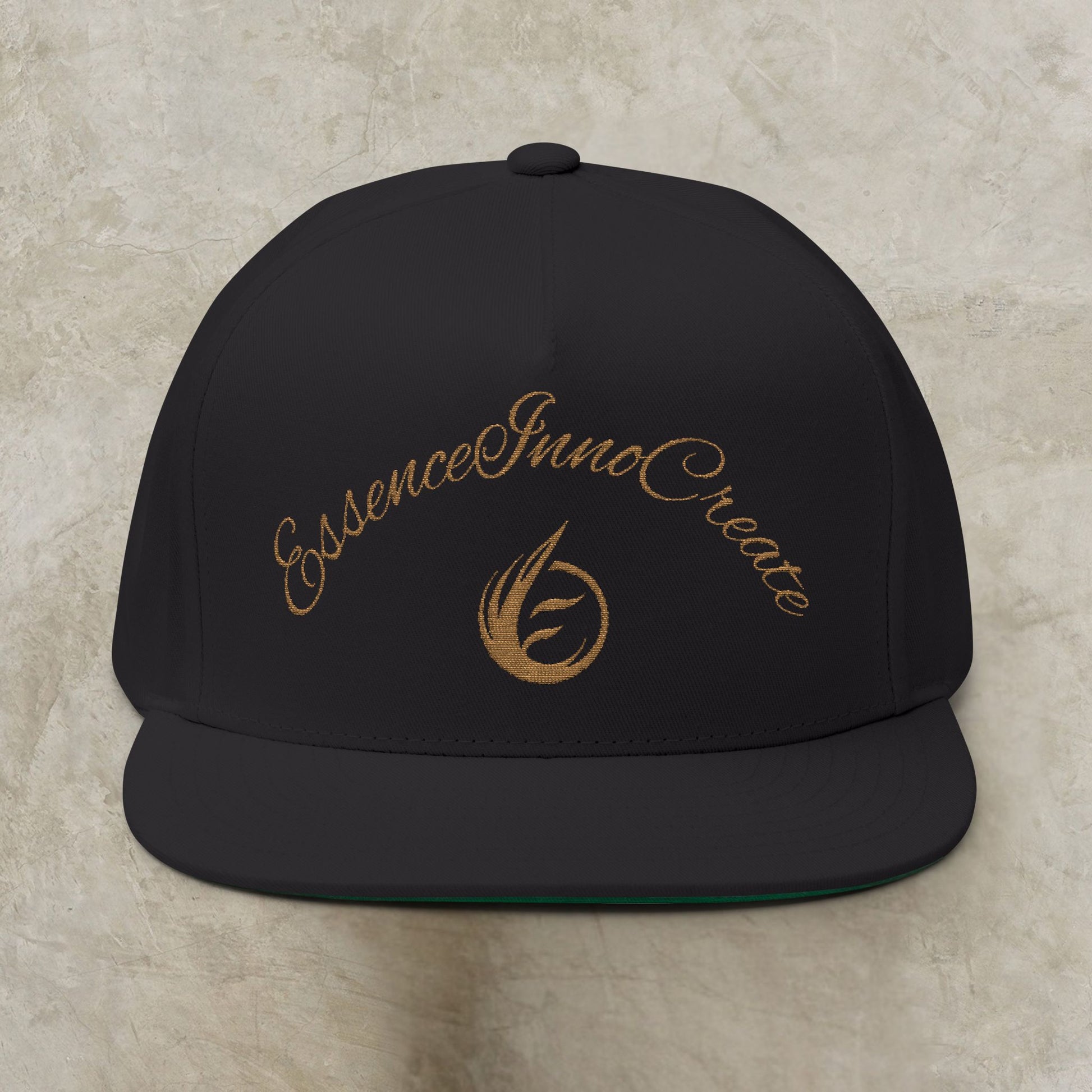 Black cap with gold EssenceInnoCreate text and logo on a beige background