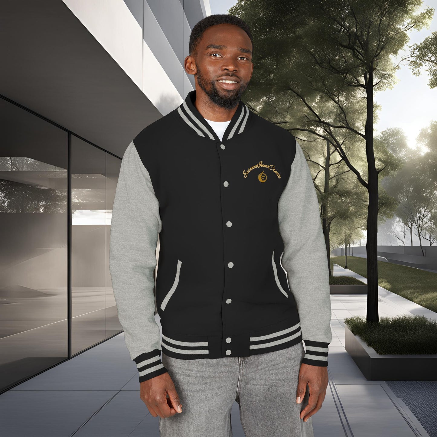 Man wearing a black and gray varsity jacket with a 'EssenceInnoCreate' logo, standing outdoors.