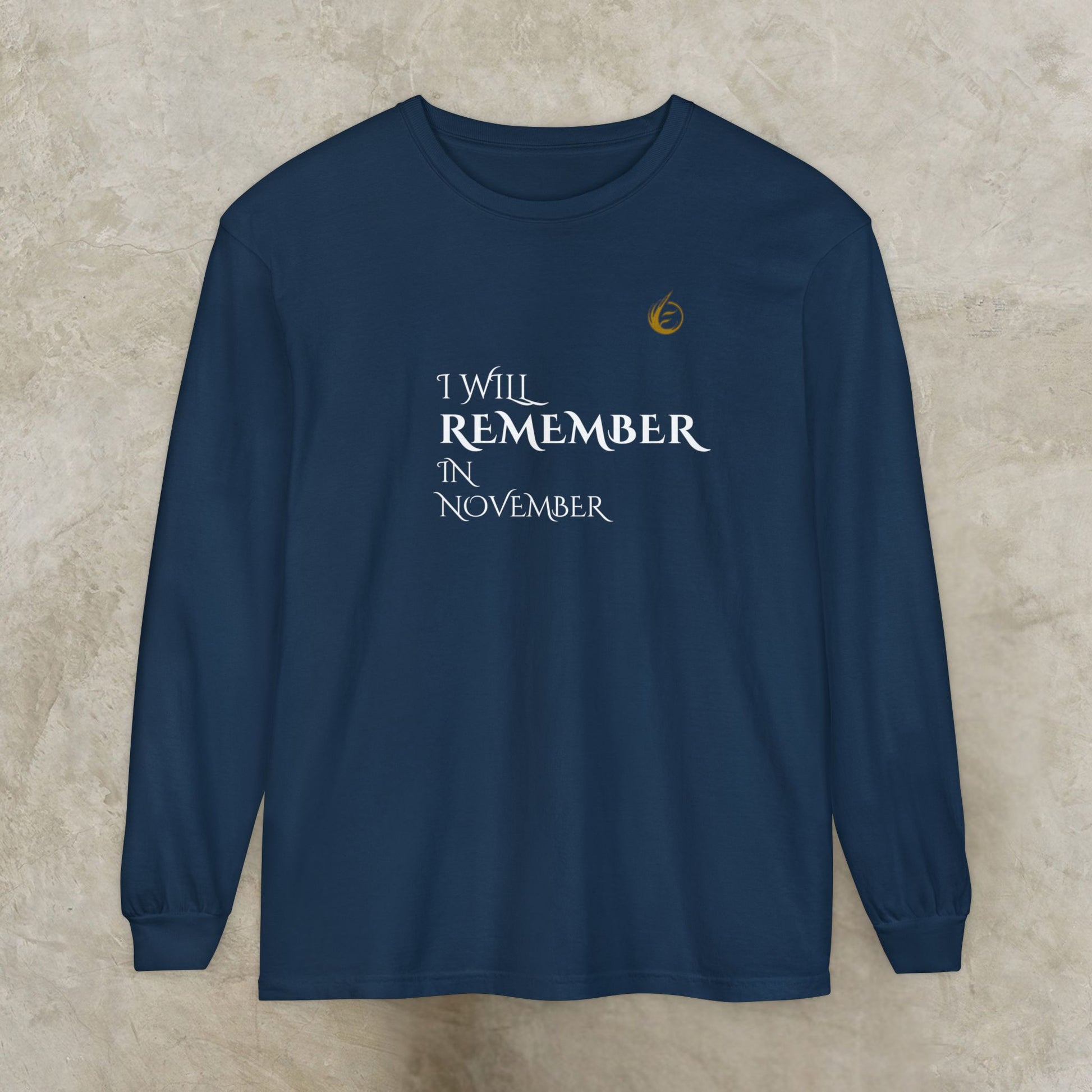 Navy blue long-sleeve EssenceInnoCreate Quiet Resolve shirt with text 'I Will Remember In November' on a beige background