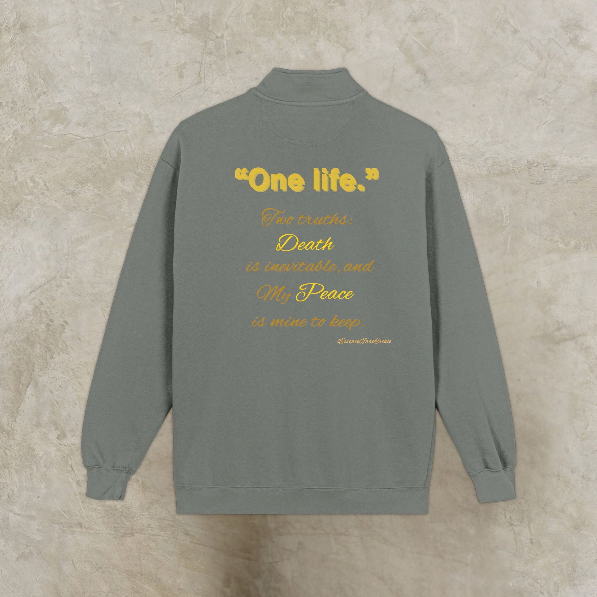 Gray sweatshirt with yellow One Life text on the back against a beige background
