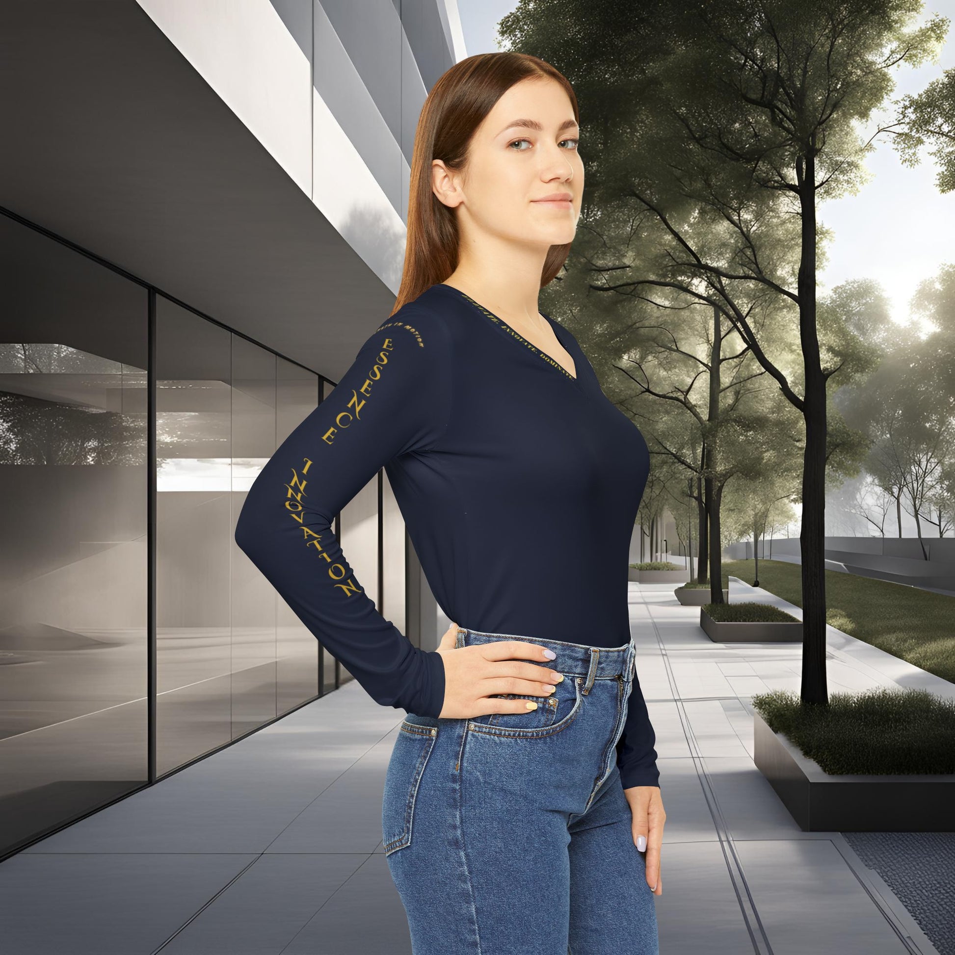 Woman wearing a navy blue long-sleeve Essence Innovation top with yellow text and blue jeans standing in an urban setting with modern architecture and trees.