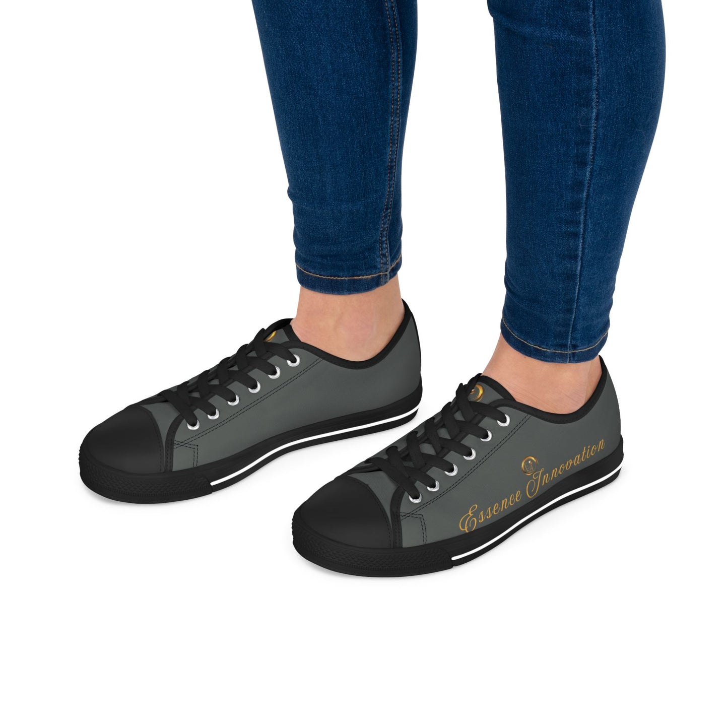 Black and gray sneakers with ''Essence Innovation' ' text worn with blue jeans on a white background