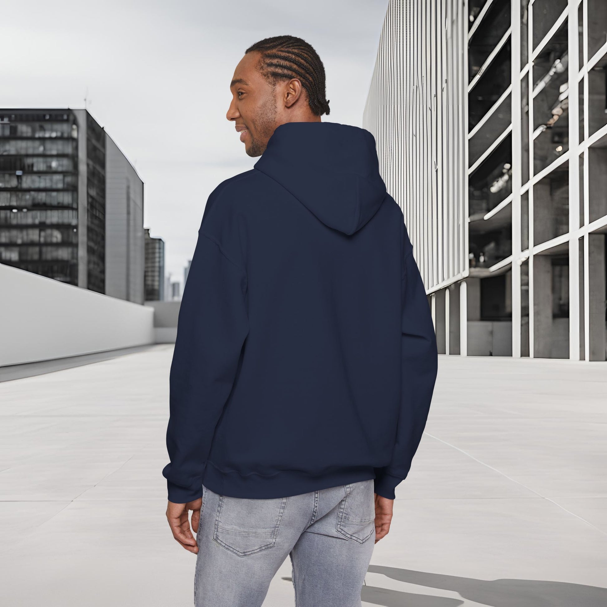 Man wearing a navy blue Essence Innovation 'One Life' hoodie standing on a rooftop with modern buildings in the background
