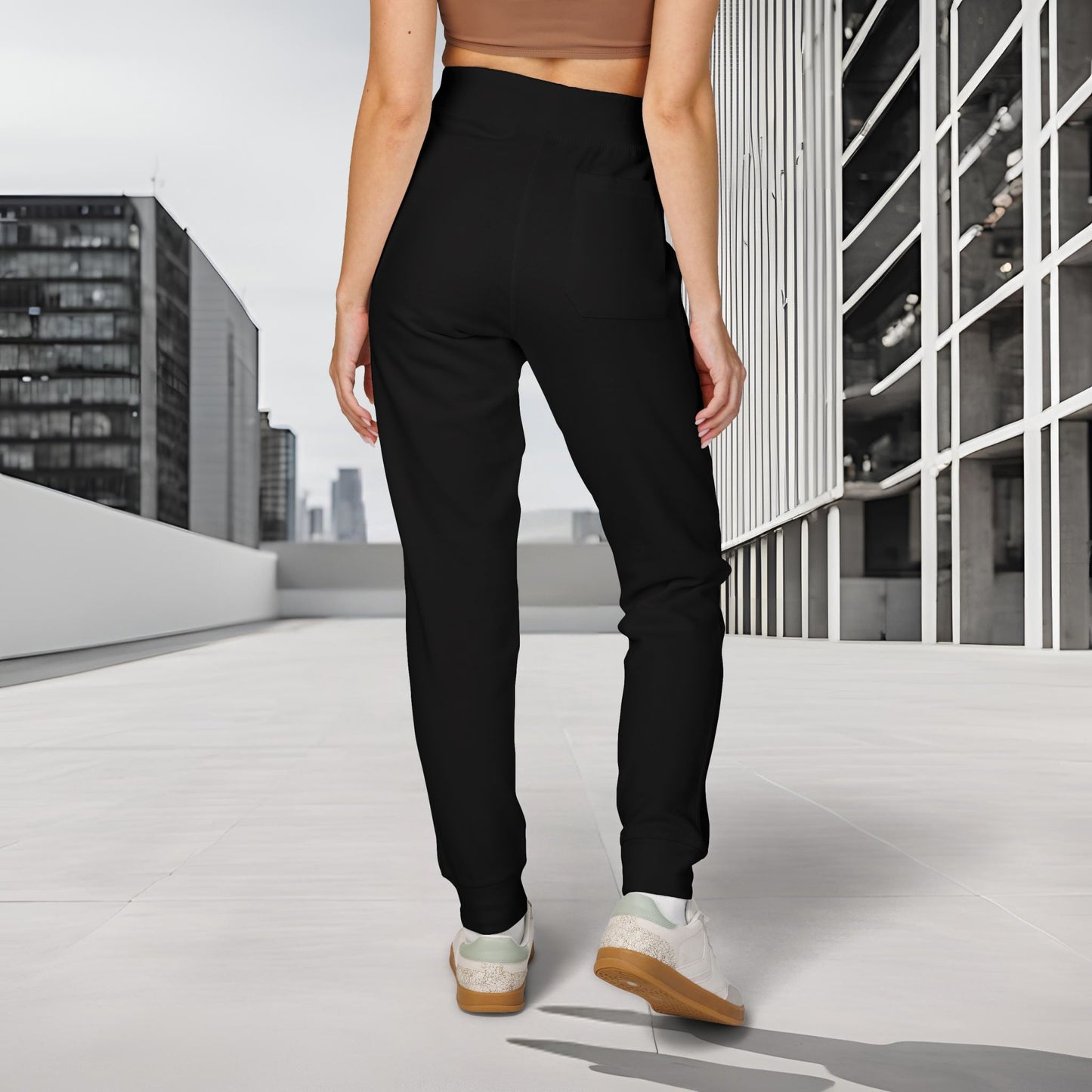 Person wearing black 'EssenceInnoCreate' Quiet Resolve pants and white sneakers standing on a rooftop with cityscape background