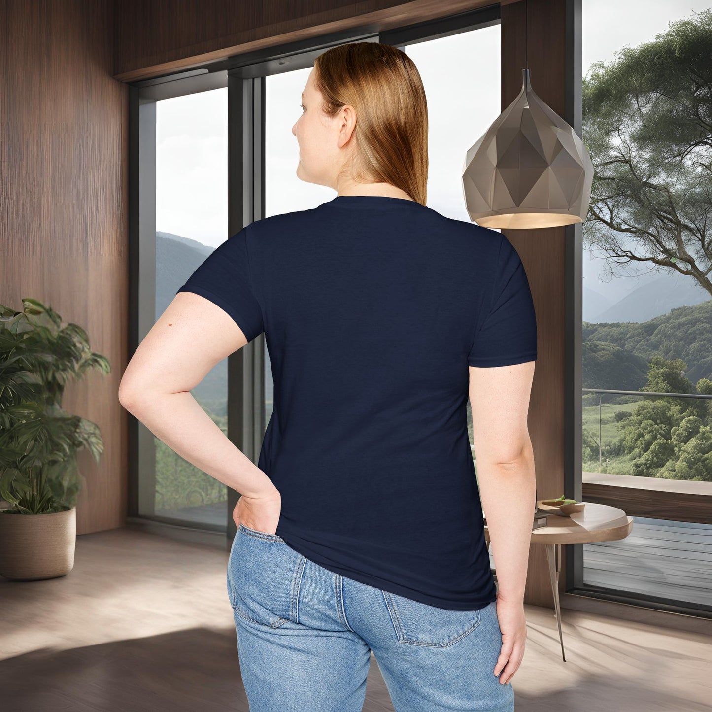 Person wearing a navy blue 'One Life' t-shirt and jeans standing in a room with large windows showing a scenic view.