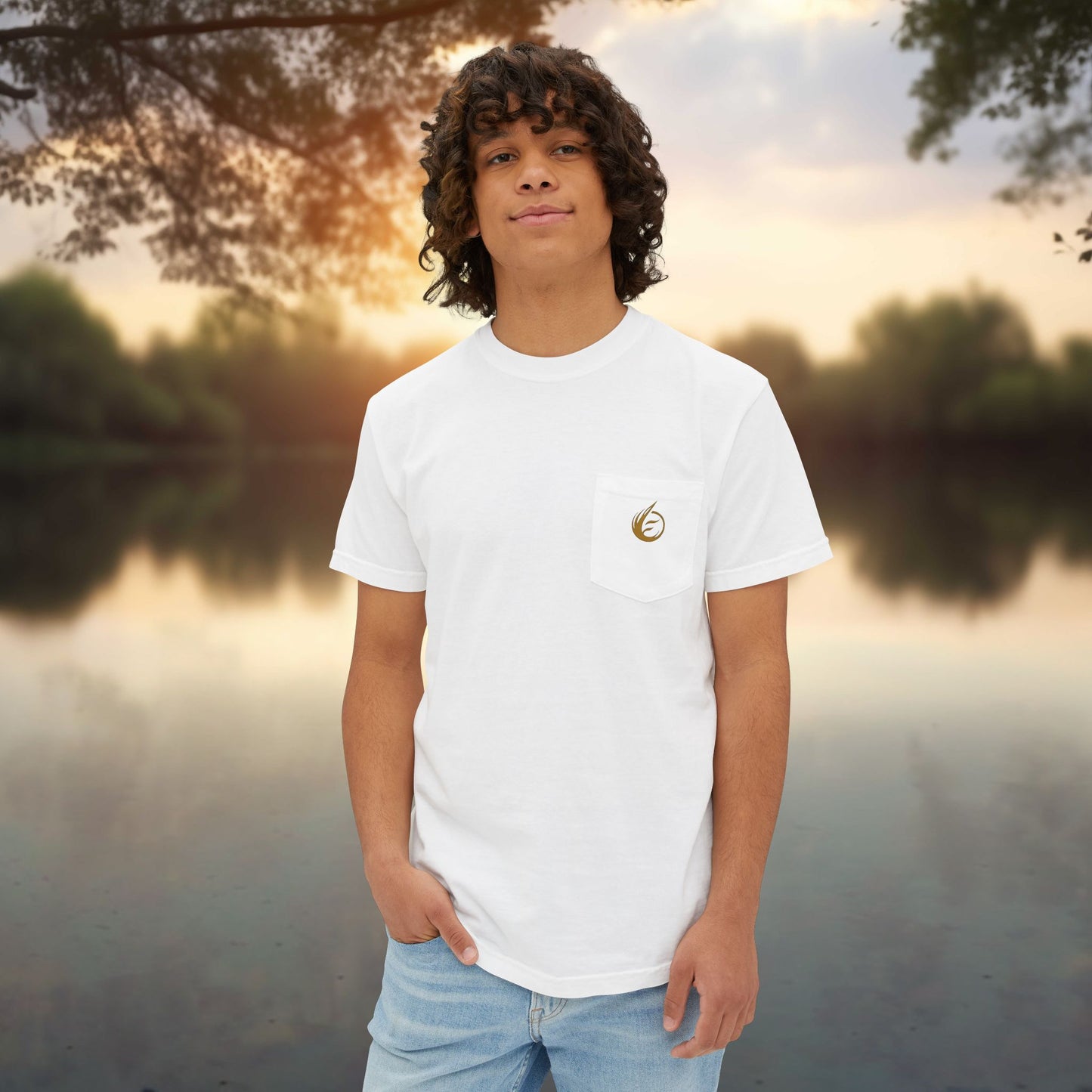 Person wearing a white t-shirt with a 'EssenceInnoCreate' logo standing by a body of water during sunset.