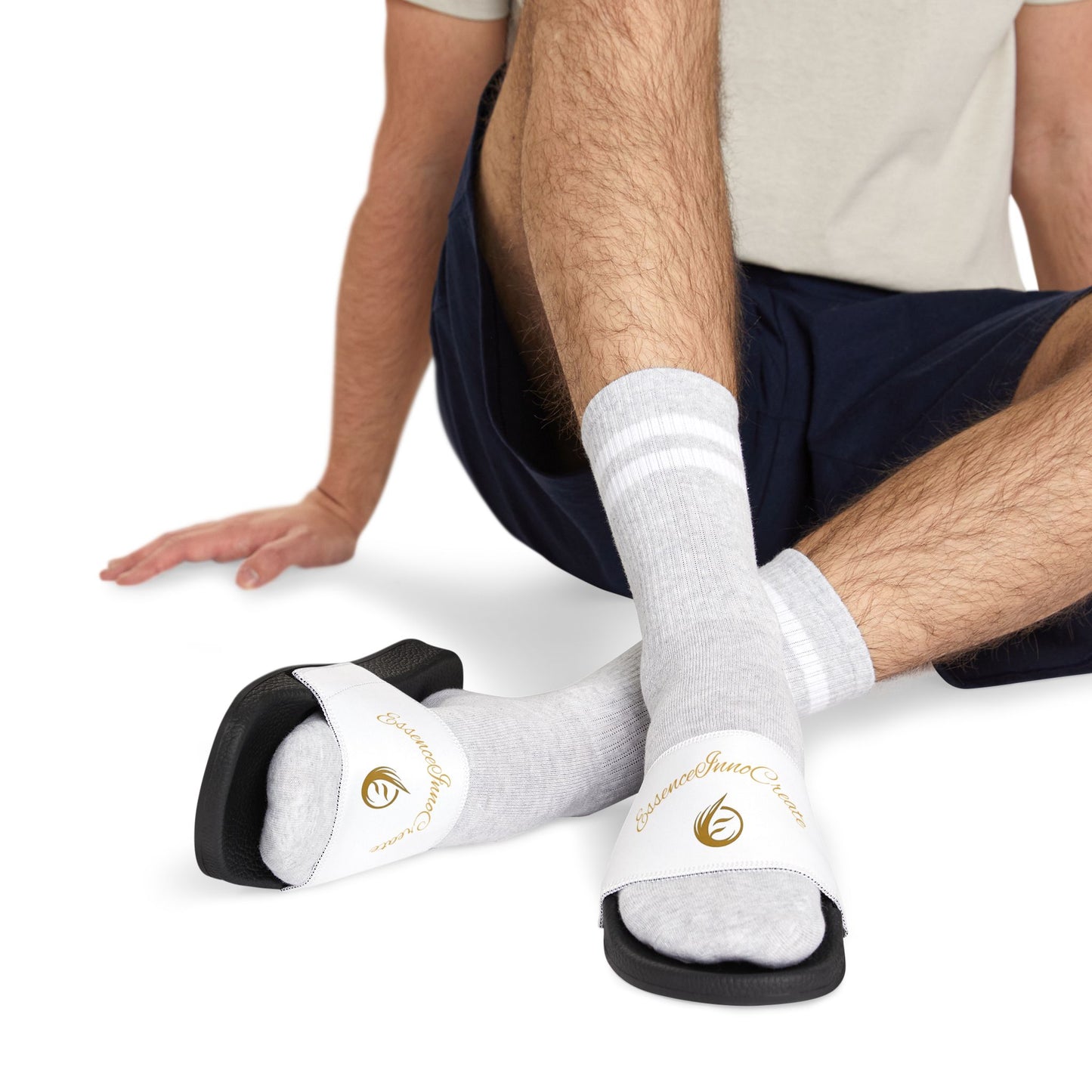 Person wearing white slides with 'EssenceInnoCreate' logo and white socks on a white background