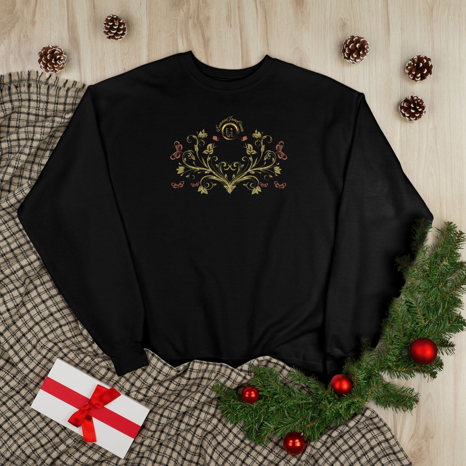 Black sweatshirt with floral Essence Innovation Bohemian Butterfly Crest design on a wooden surface with Christmas decorations.