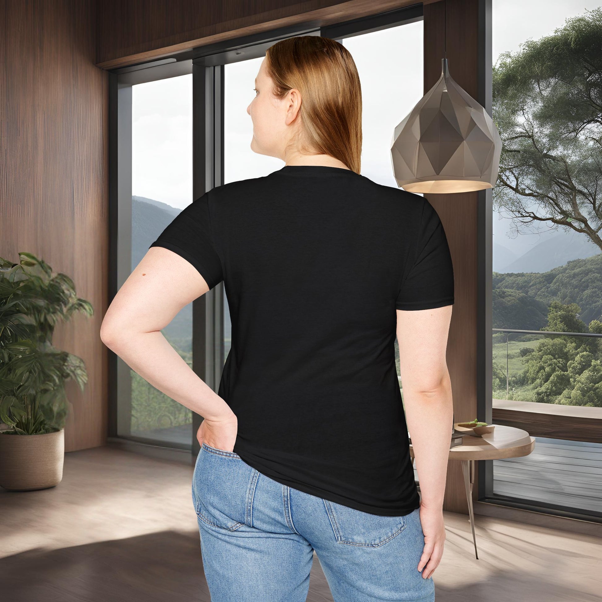 Person wearing a black Essence Innovation 'Design Meets Soul' t-shirt in a modern room with large windows