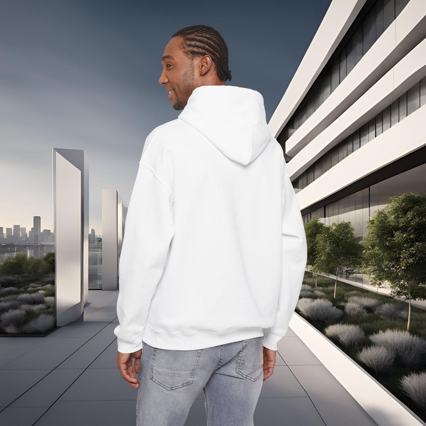 Man wearing a white 'EssenceInnoCreate' hoodie standing in front of a modern building with greenery.