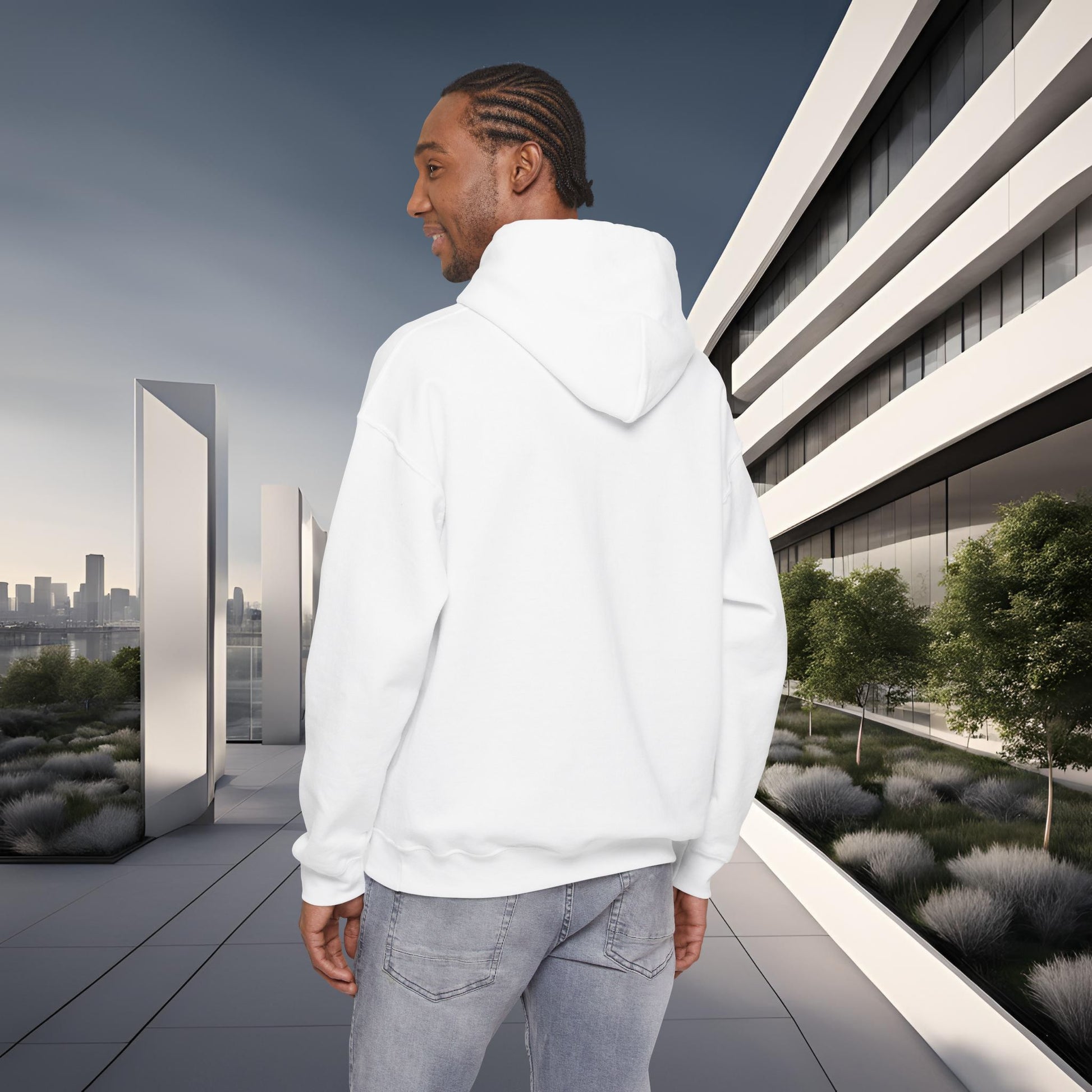 Man wearing a white 'EssenceInnoCreate' hoodie standing in front of a modern building with greenery.