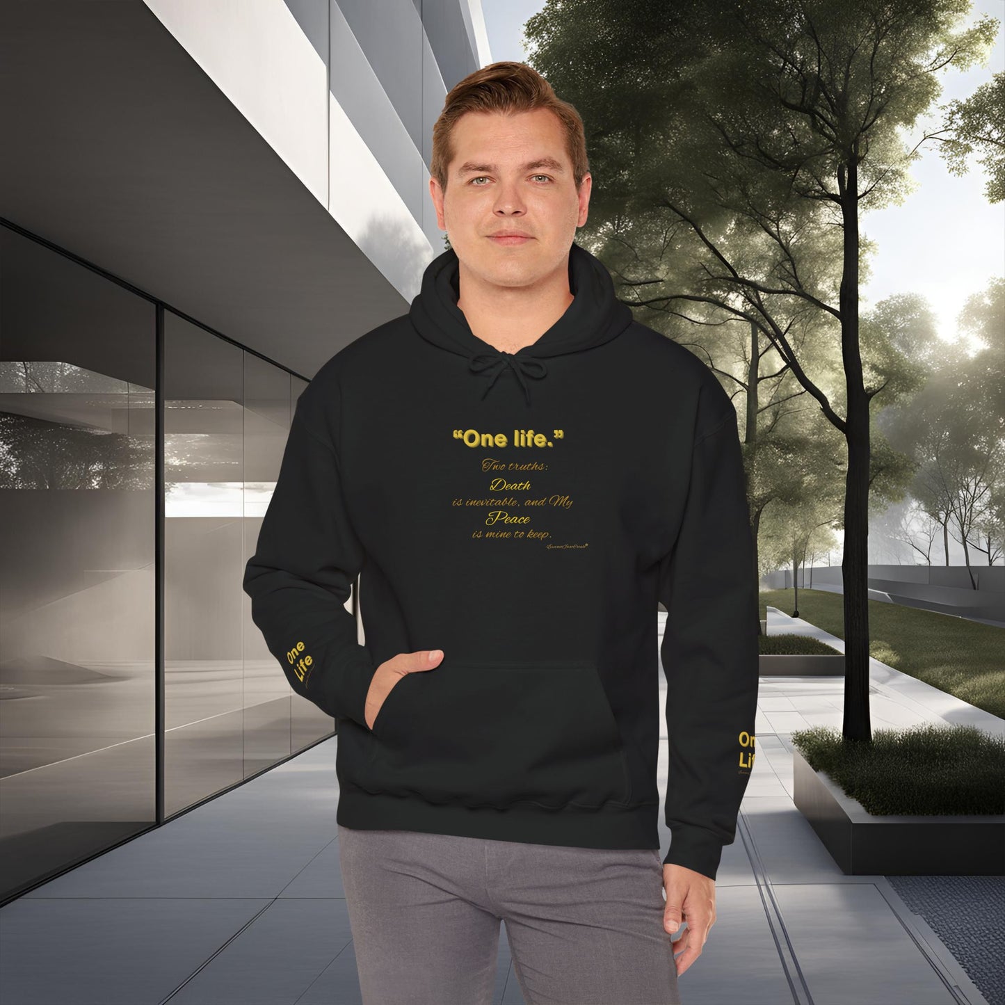 Man wearing a black Essence Innovation 'One Life' hoodie with yellow text in an outdoor setting