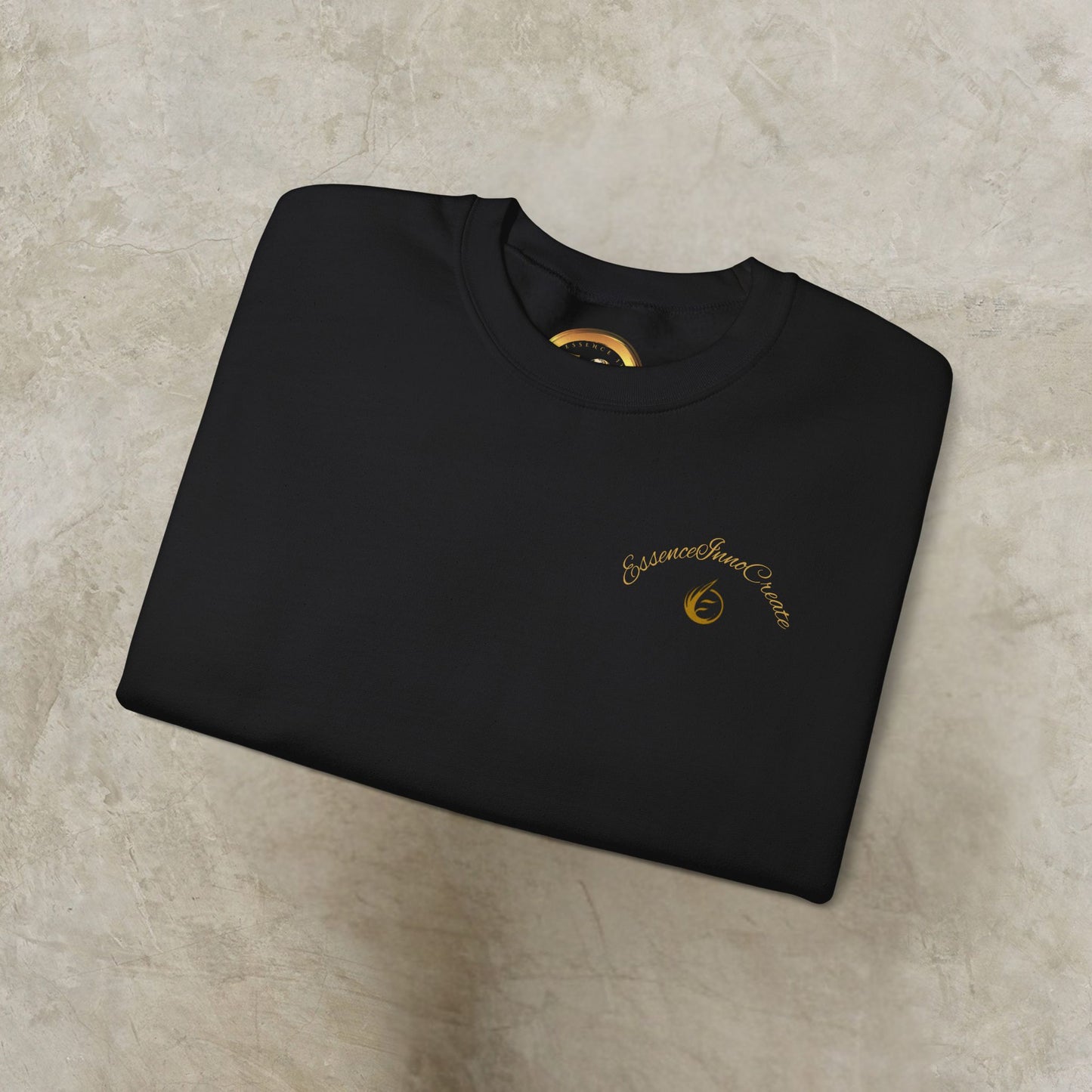 Folded black sweatshirt with 'EssenceInnoCreate' logo on a beige surface