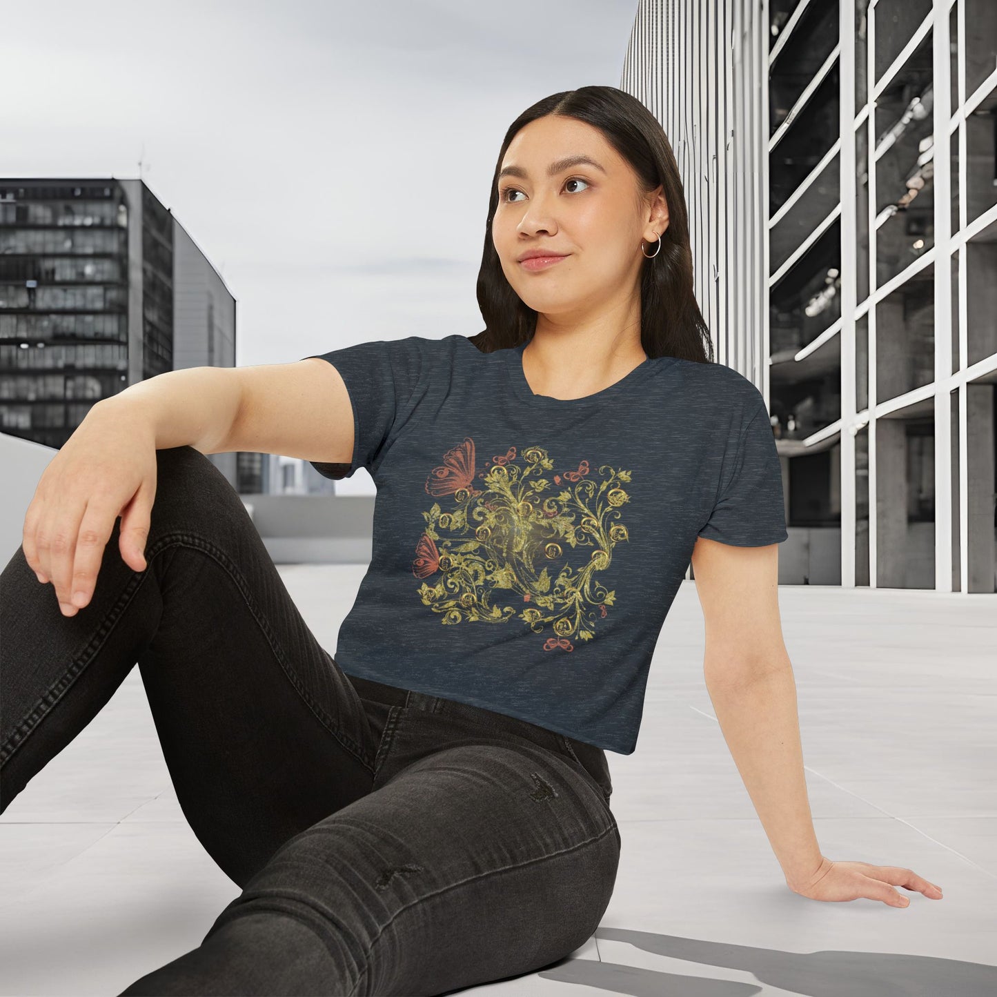 Woman wearing a dark blue t-shirt with a colorful Essence Innovation Bohemian Butterfly design, sitting on a bench in an urban setting.