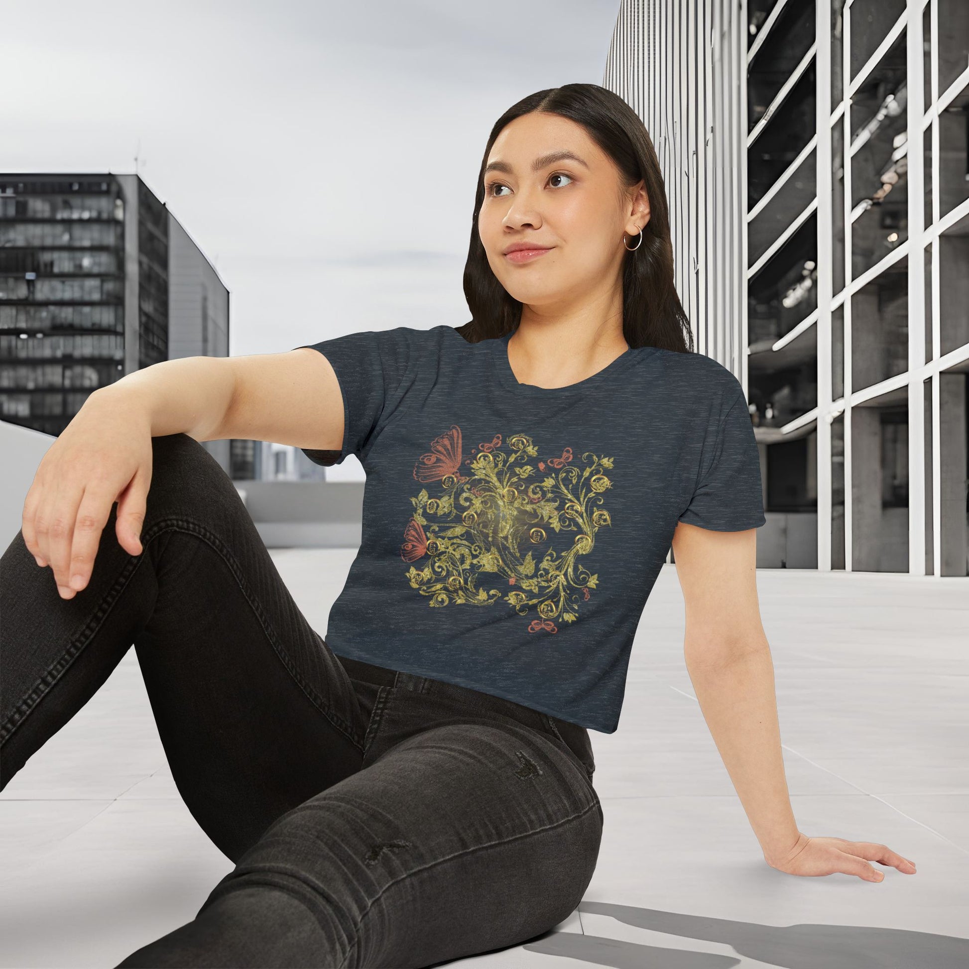 Woman wearing a dark blue t-shirt with a colorful Essence Innovation Bohemian Butterfly design, sitting on a bench in an urban setting.