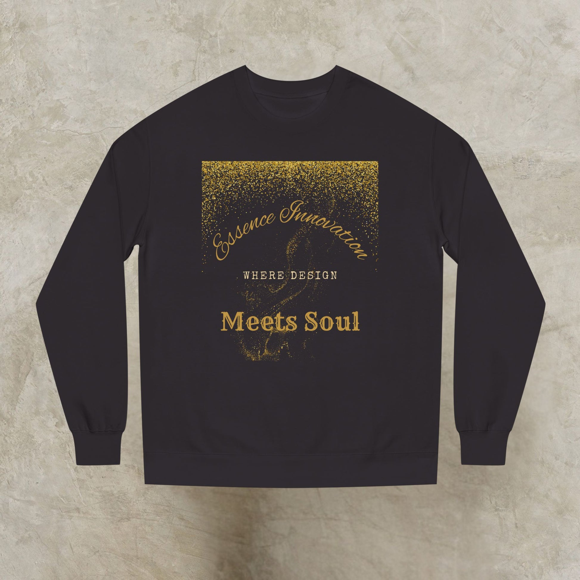Black sweatshirt with gold Essence Innovation 'Design Meets Soul' text on a textured beige background