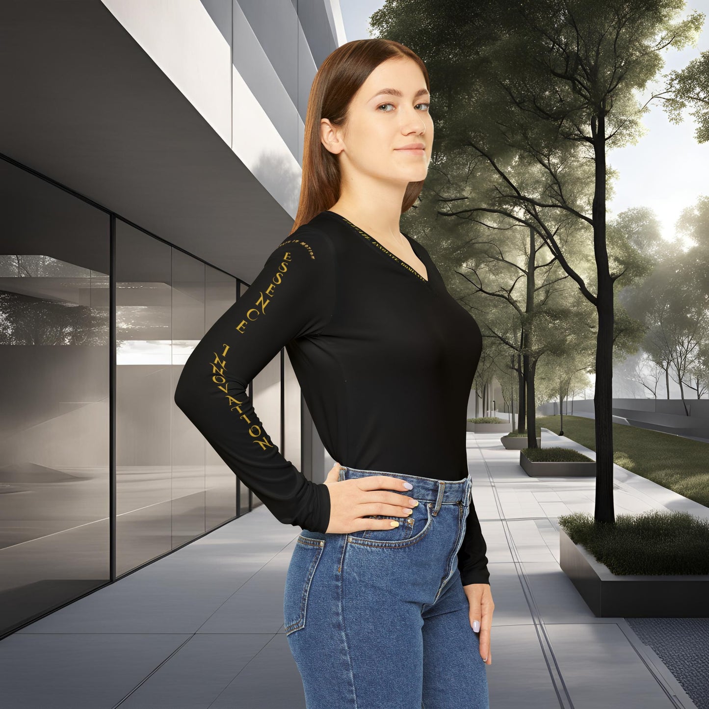 Woman wearing a black Essence Innovation Seek More long-sleeve top with gold text and blue jeans standing in an urban setting.