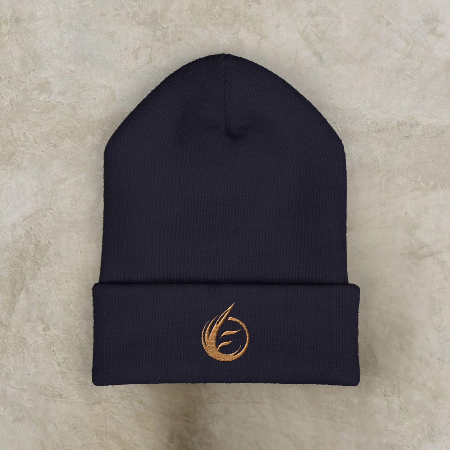 Black beanie with a gold EssenceInnoCreate logo on a beige surface
