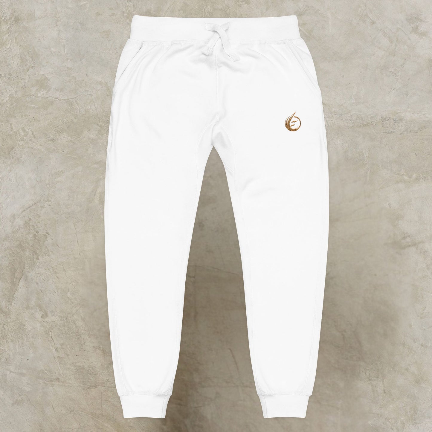 White sweatpants with a gold 'EssenceInnoCreate' Quiet Resolve logo on a beige background