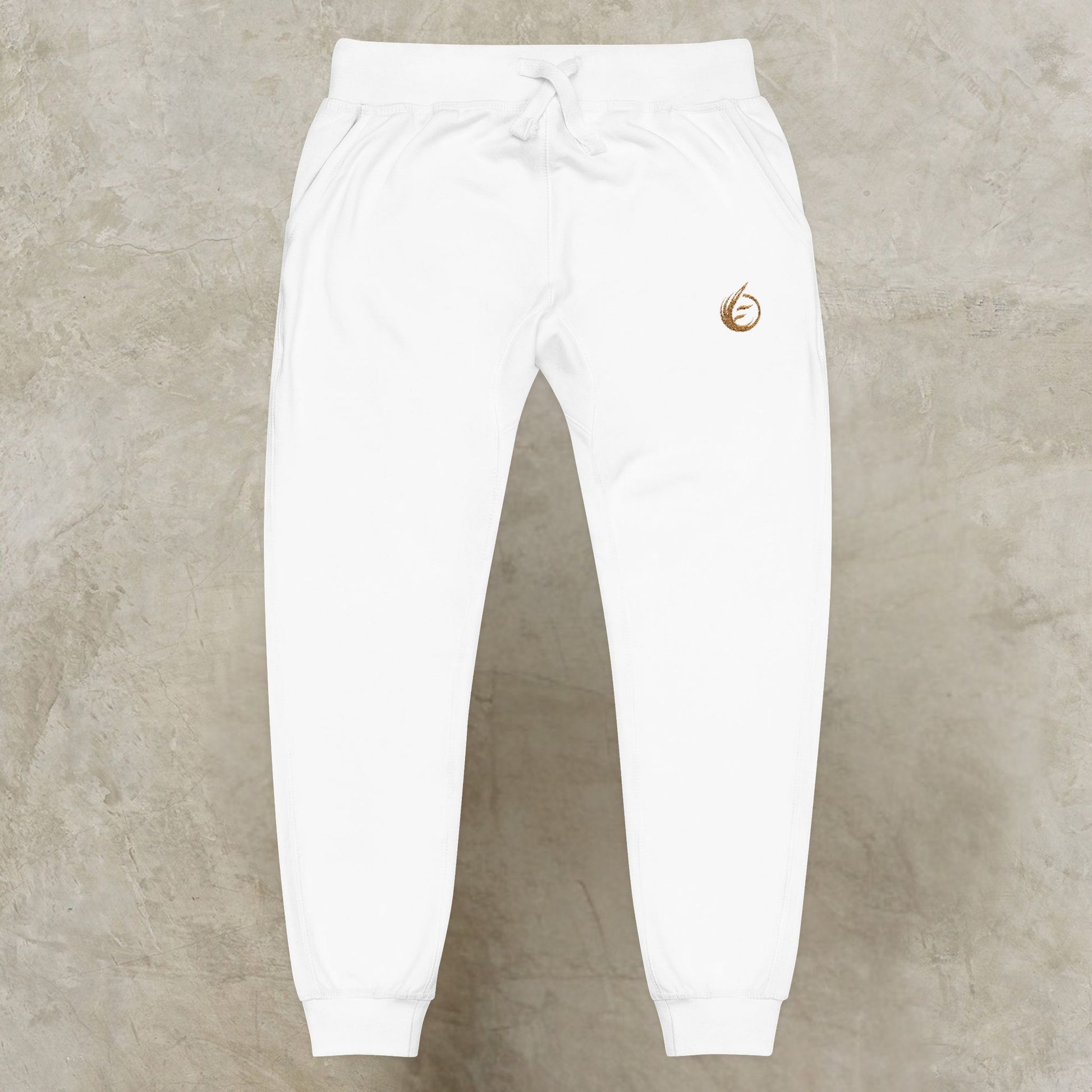 White sweatpants with a gold 'EssenceInnoCreate' Quiet Resolve logo on a beige background