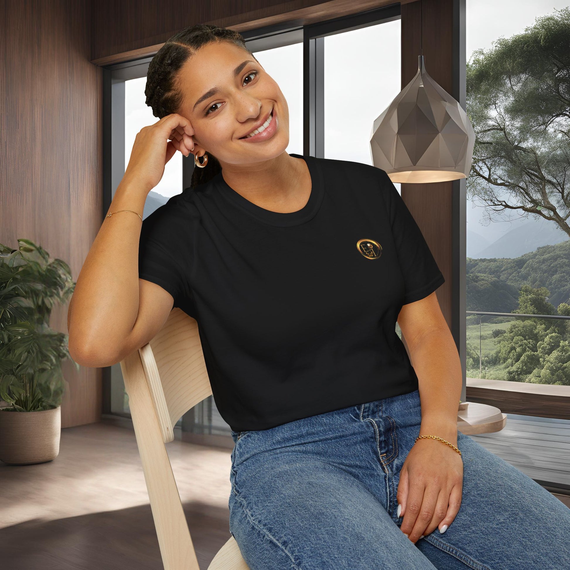 Woman wearing a black t-shirt with an Essence Innovation logo, sitting indoors with a scenic view outside.