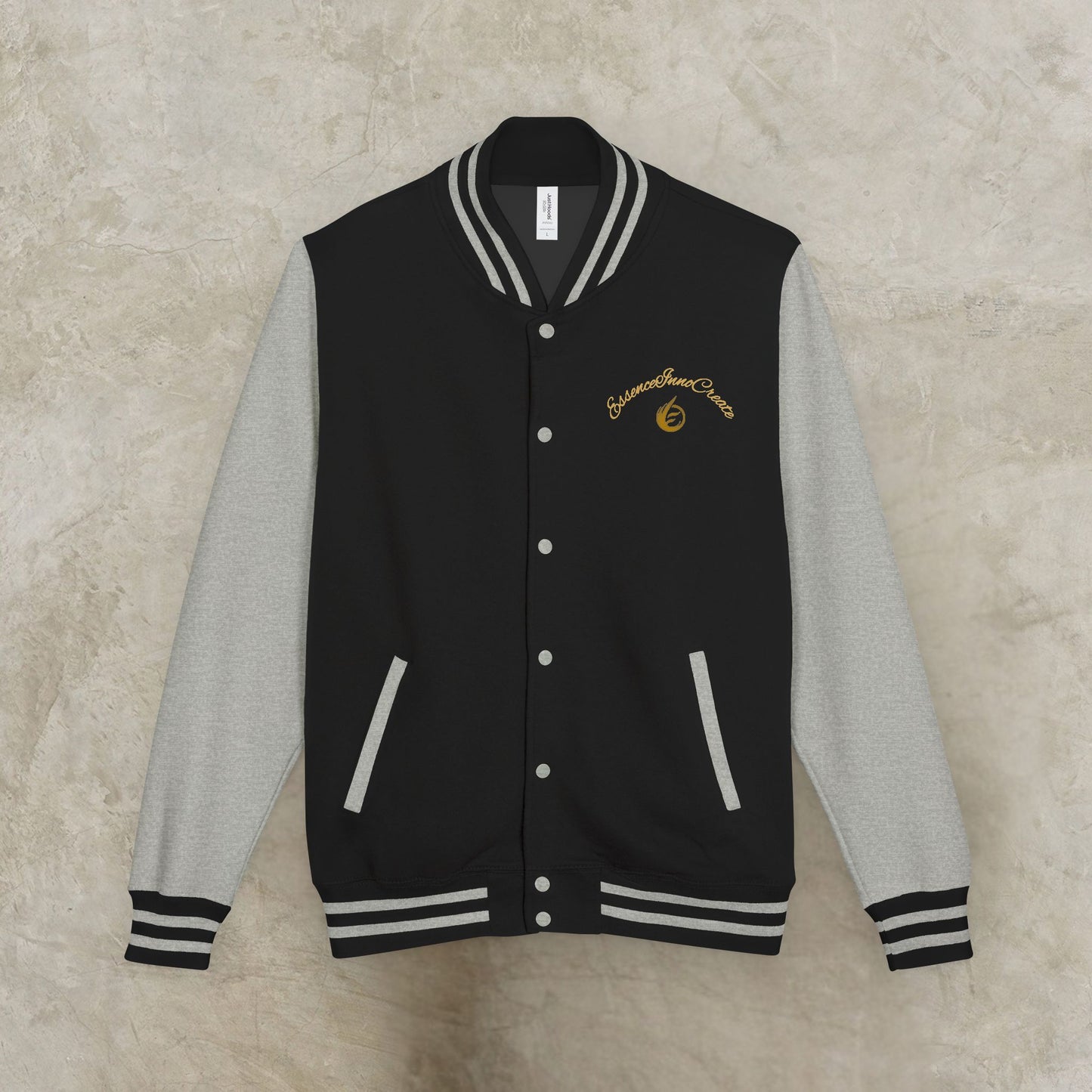 Black and gray varsity jacket with a EssenceInnoCreate logo on a beige background