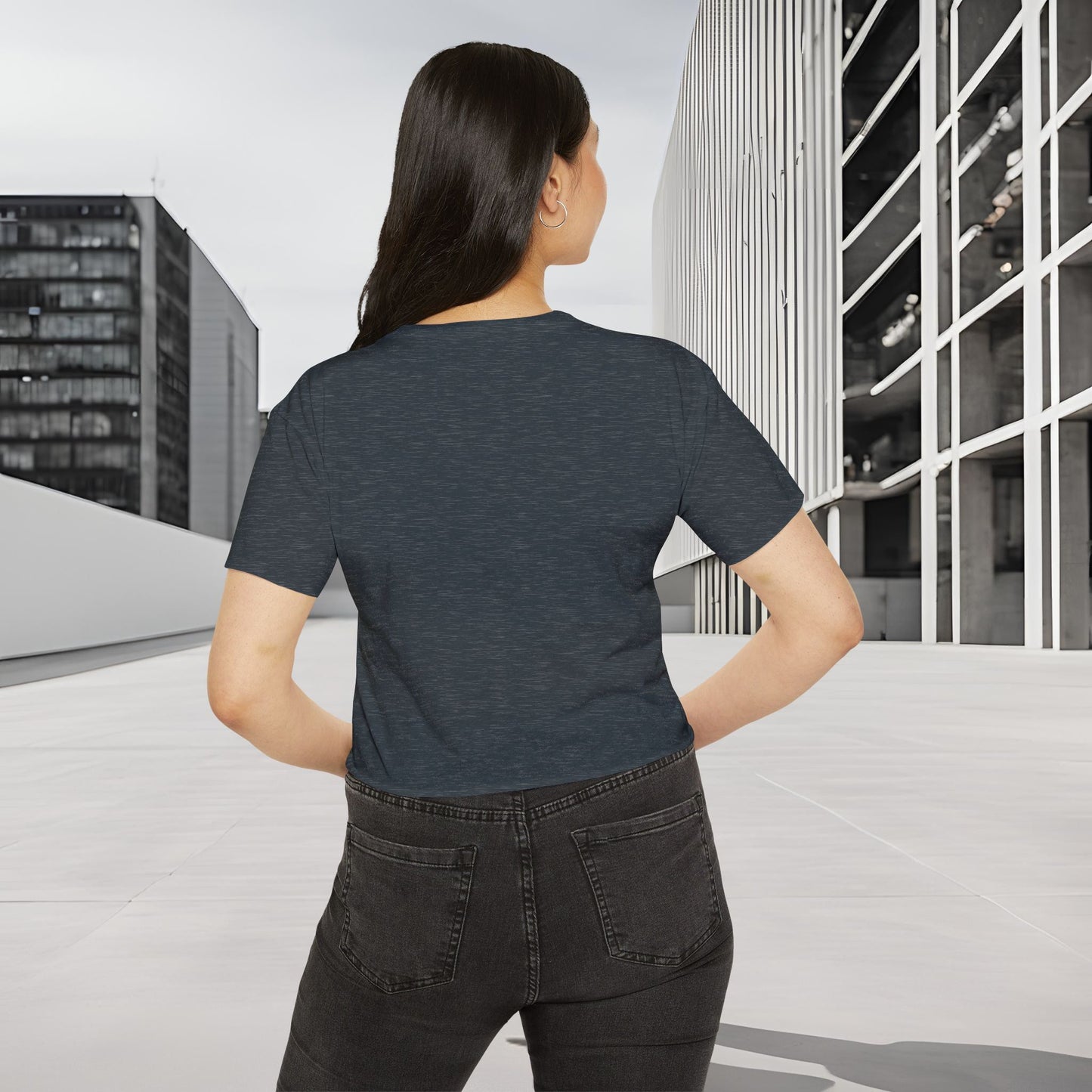 Person wearing a dark gray Essence Innovation Bohemian Butterfly t-shirt and black pants standing on a rooftop with cityscape background