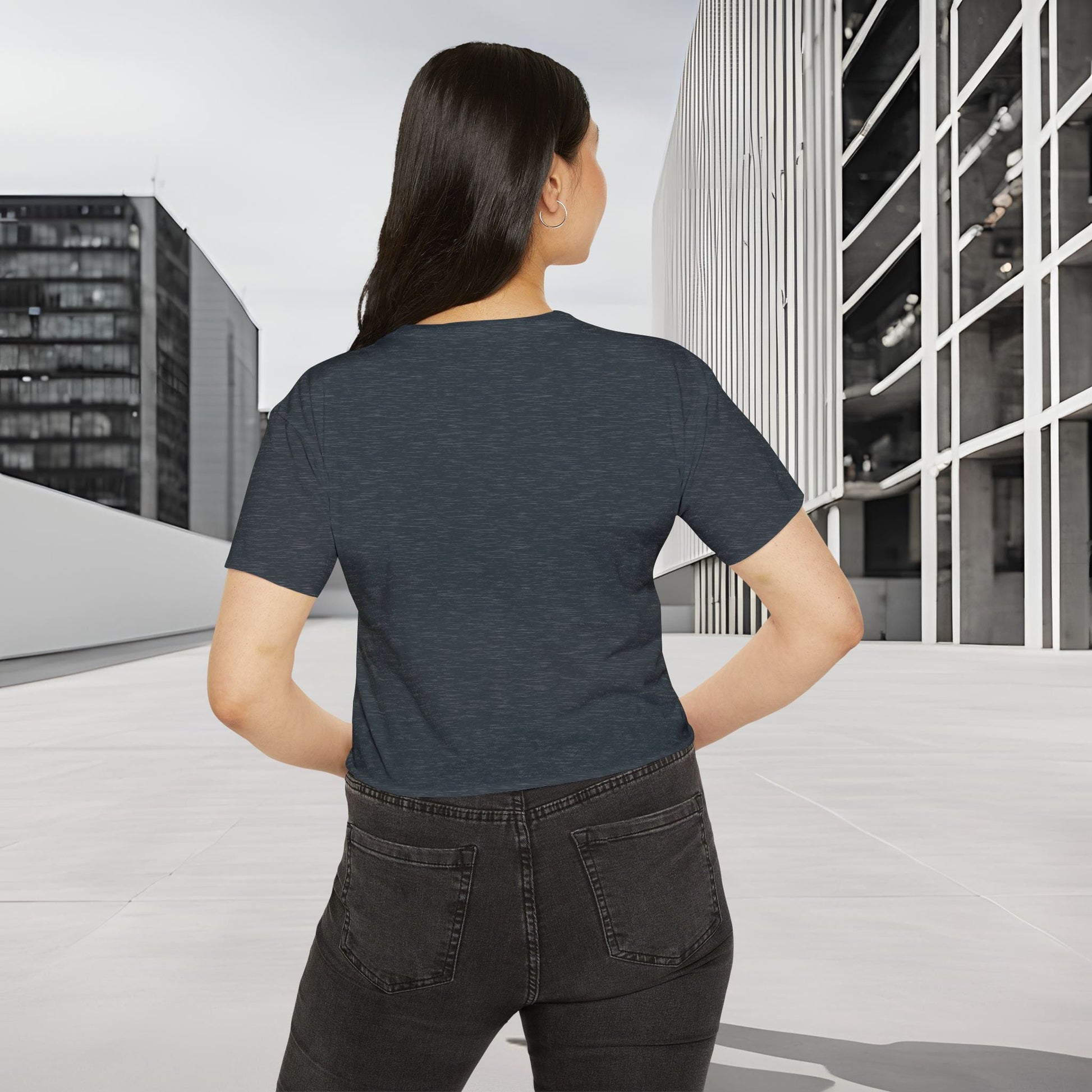 Person wearing a dark gray Essence Innovation Bohemian Butterfly t-shirt and black pants standing on a rooftop with cityscape background