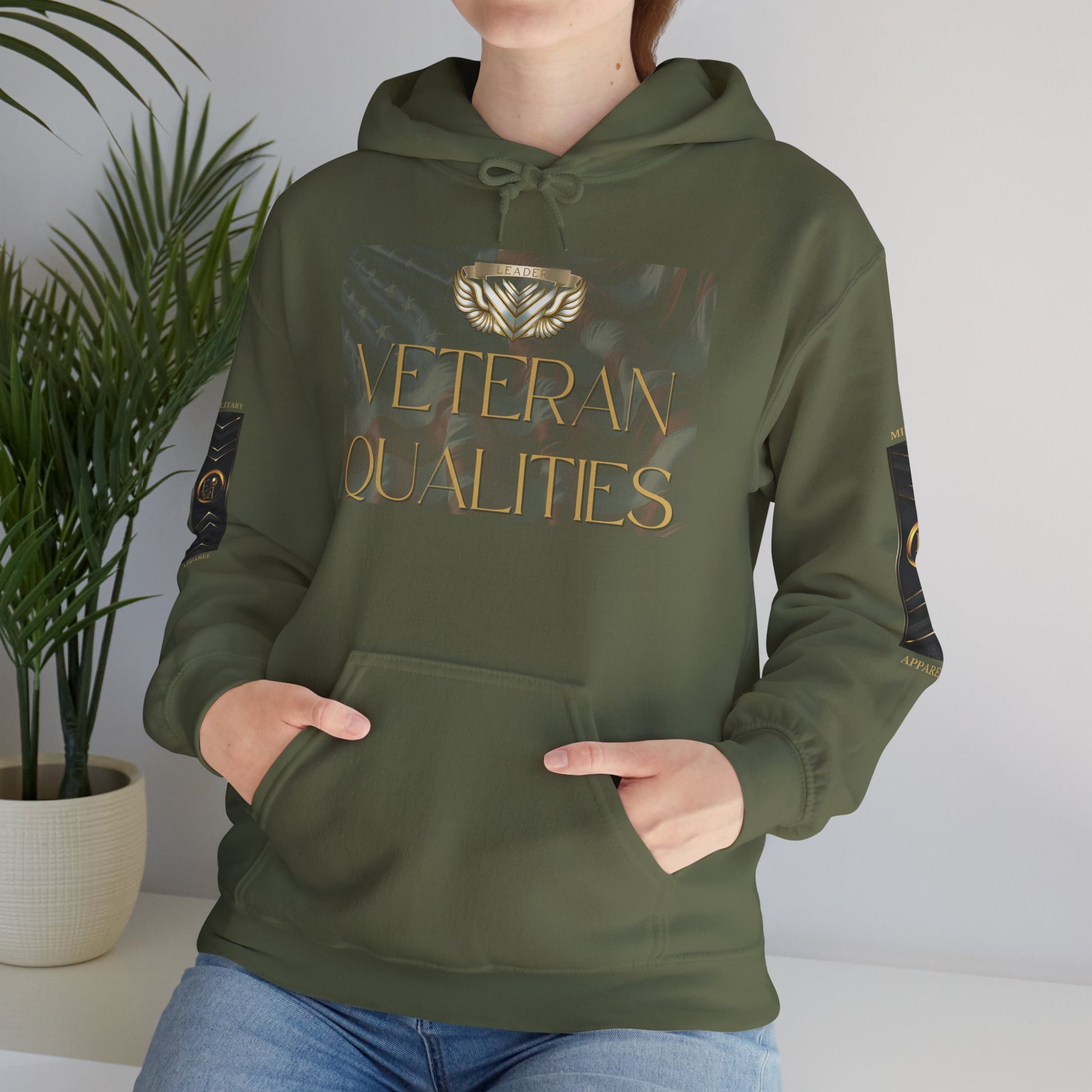 Person wearing a green Essence Innovation hoodie with 'Veteran Qualities' text, standing indoors next to a plant.