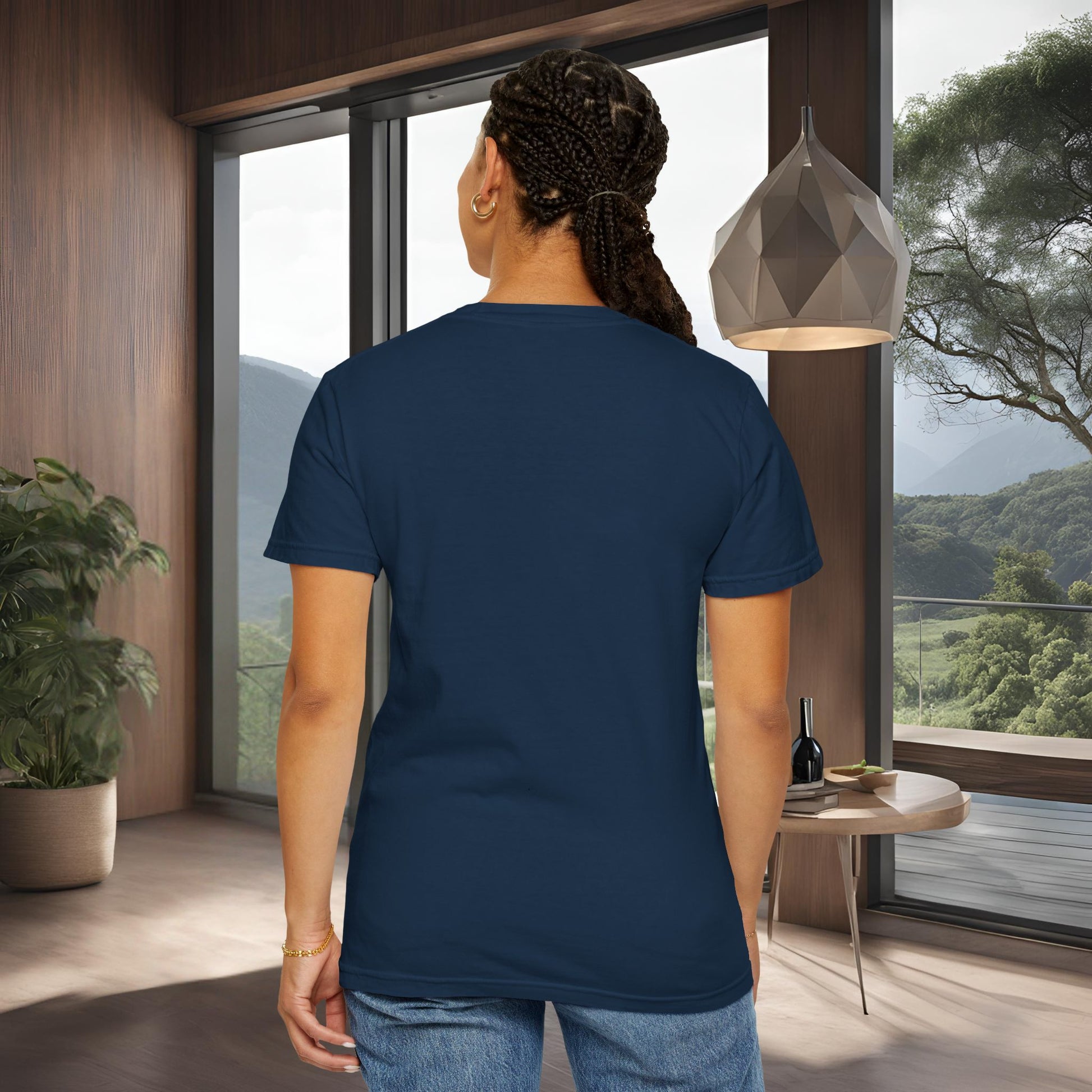 Person wearing a black 'EssenceInnoCreate' t-shirt in a modern room with large windows and a view of trees.