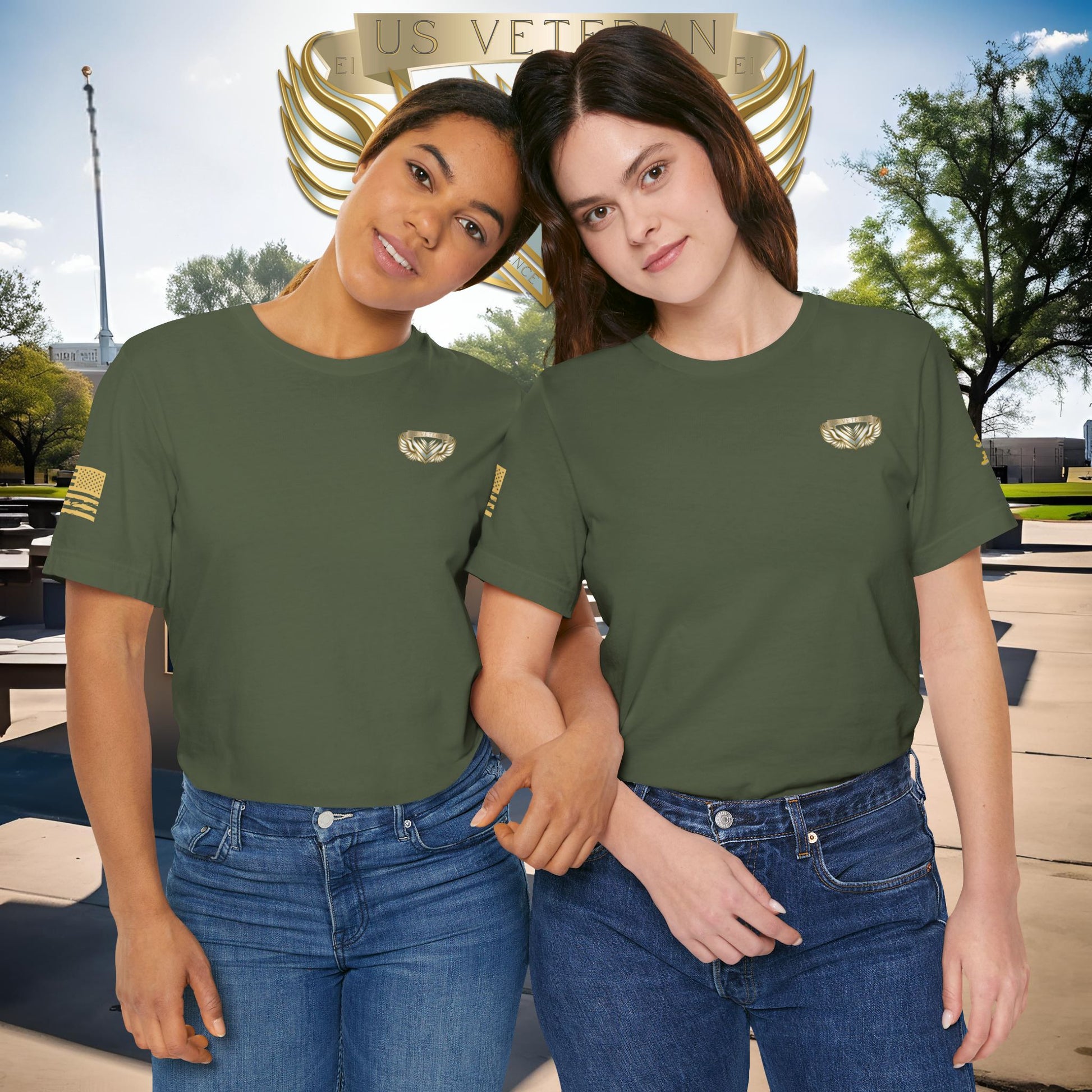 Two women wearing green t-shirts with a logo, standing in front of a U.S. Veterans monument.