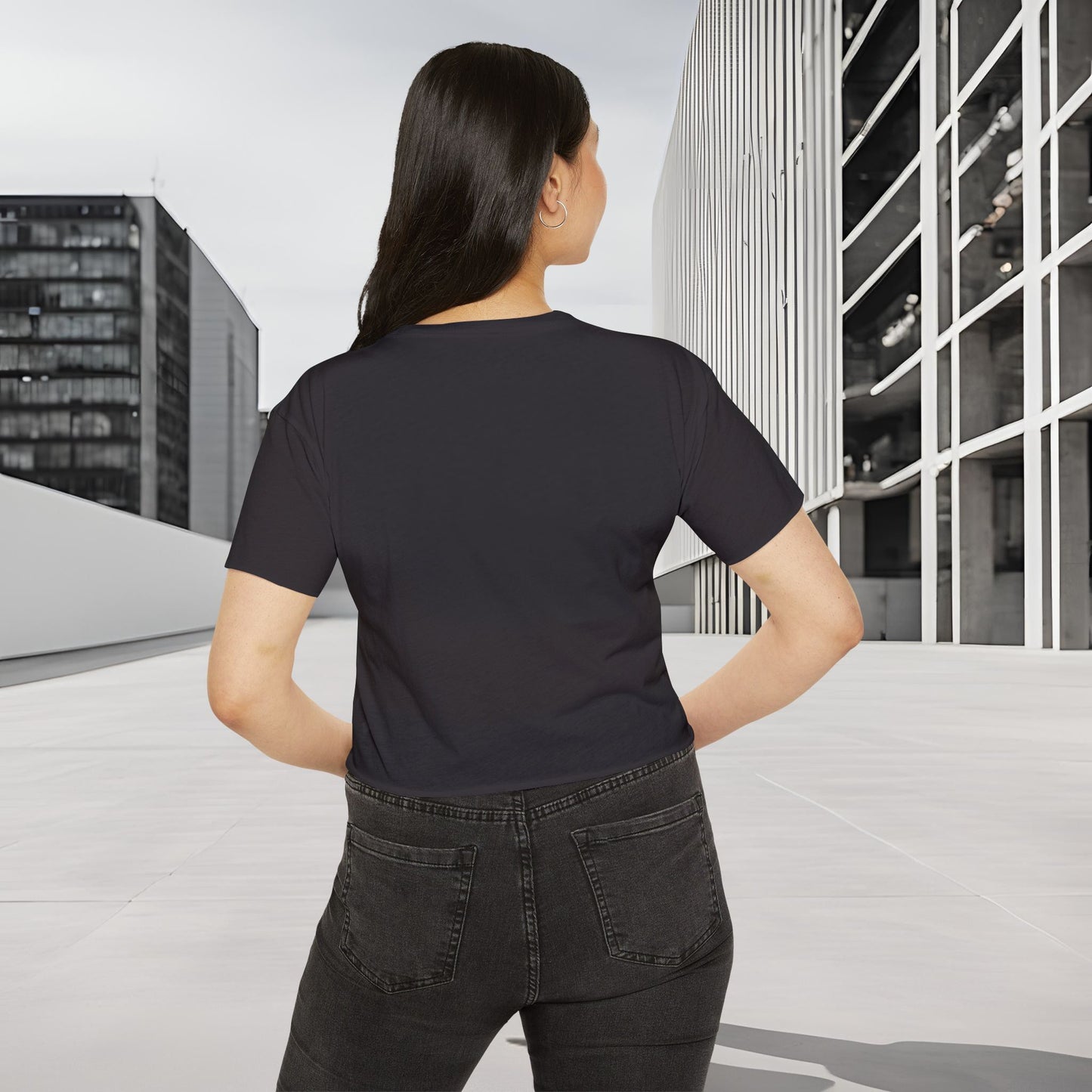 Person wearing a black Essence Innovation 'Design Meets Soul' t-shirt and jeans standing in an urban setting with modern buildings.