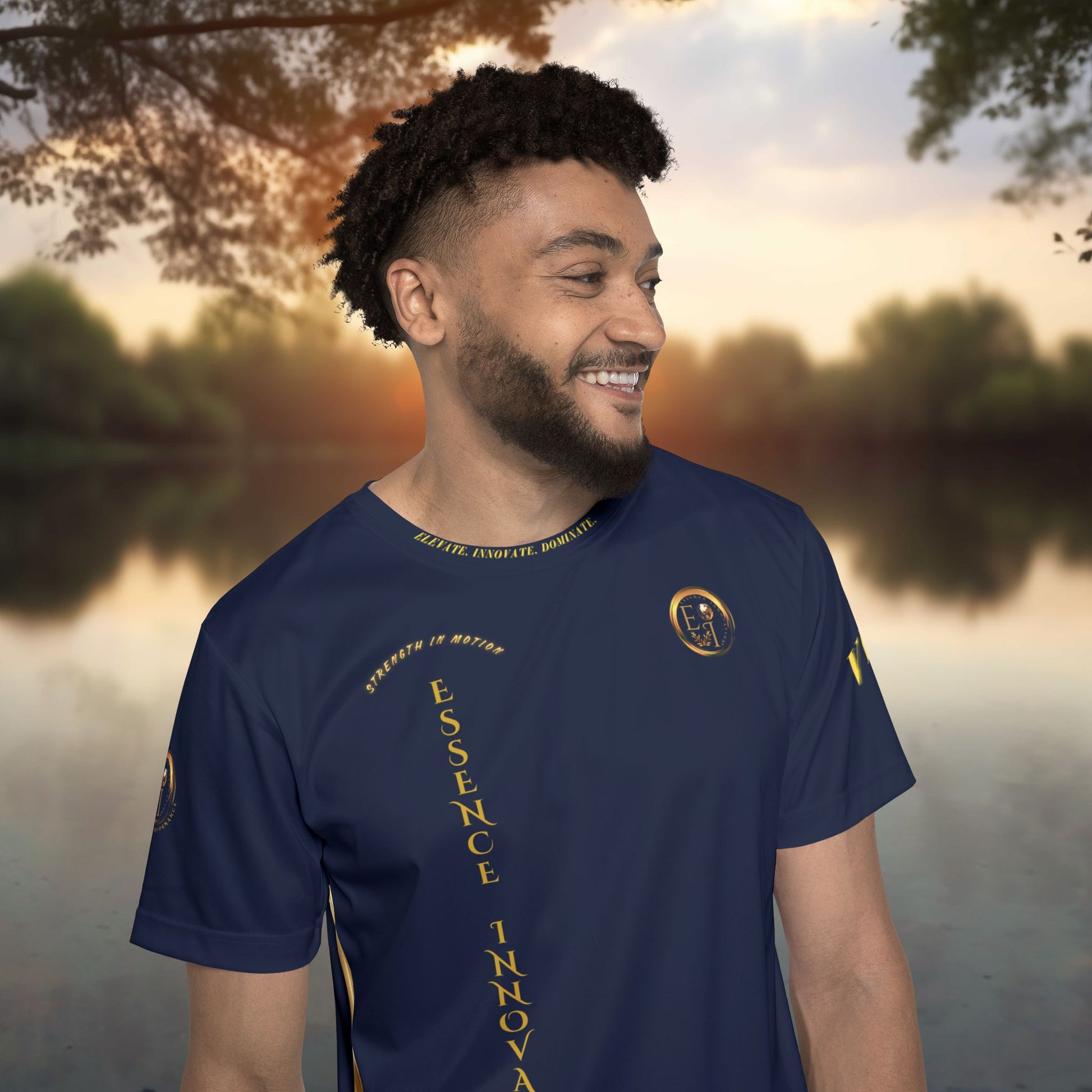 Man wearing a navy blue t-shirt with yellow Essence Innovation logo and text and graphics, standing outdoors with a blurred natural background.
