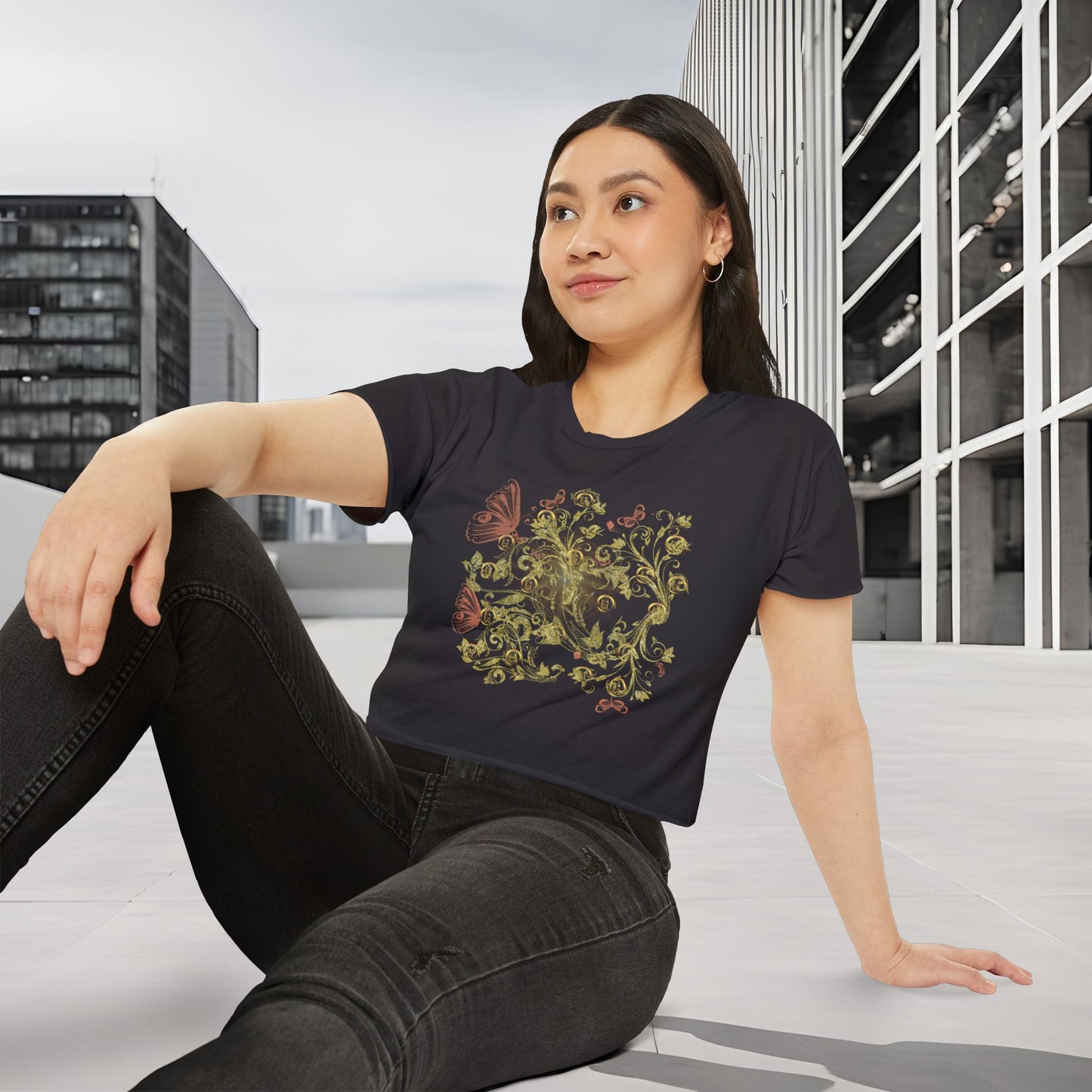 Woman wearing a black t-shirt with a colorful Essence Innovation Bohemian Butterfly design, sitting on a bench in an urban setting.