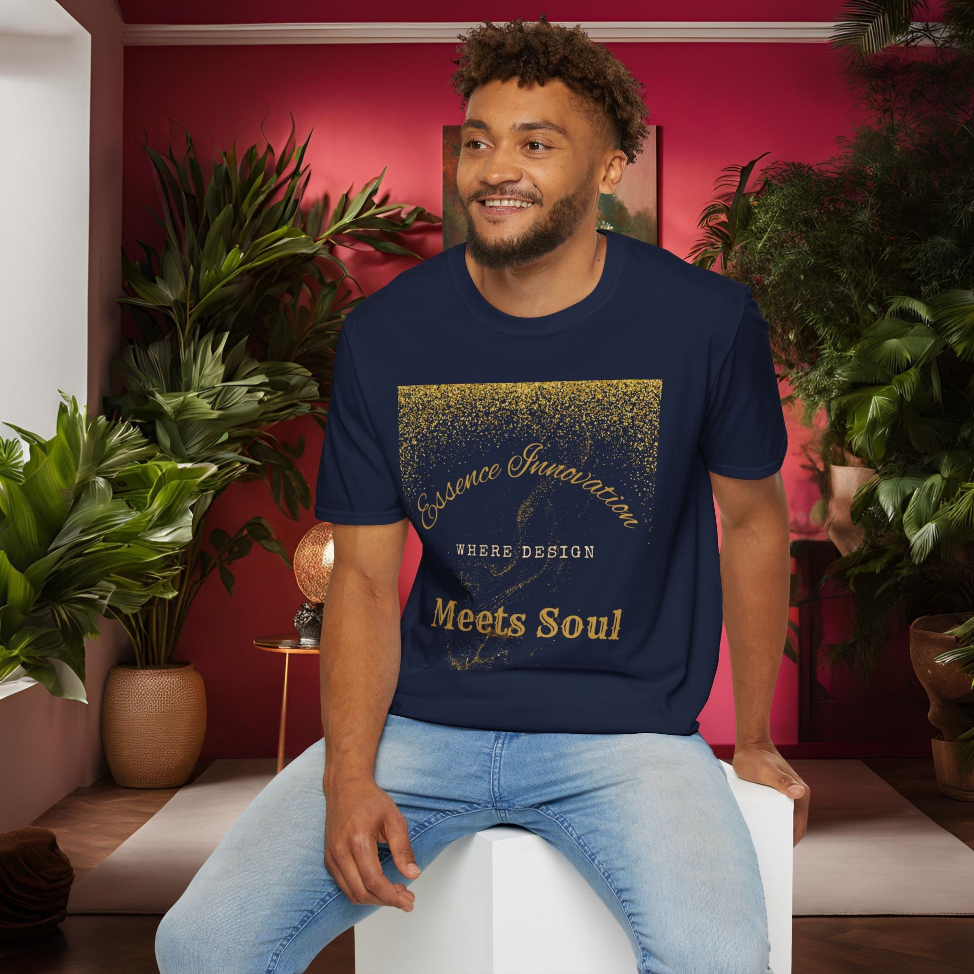 Man wearing a navy blue t-shirt with gold Essence Innovation 'Design Meets Soul' text in a room with plants and a red wall.