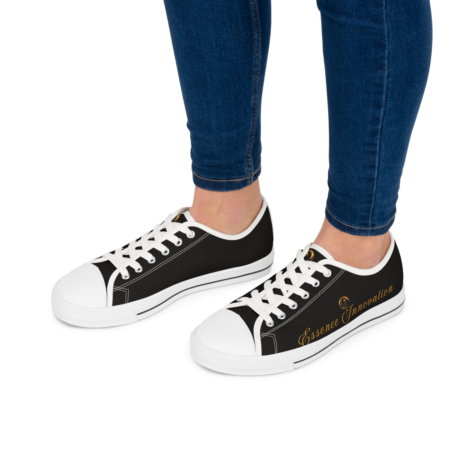 Black Essence Innovation sneakers with white soles worn with blue jeans on a white background