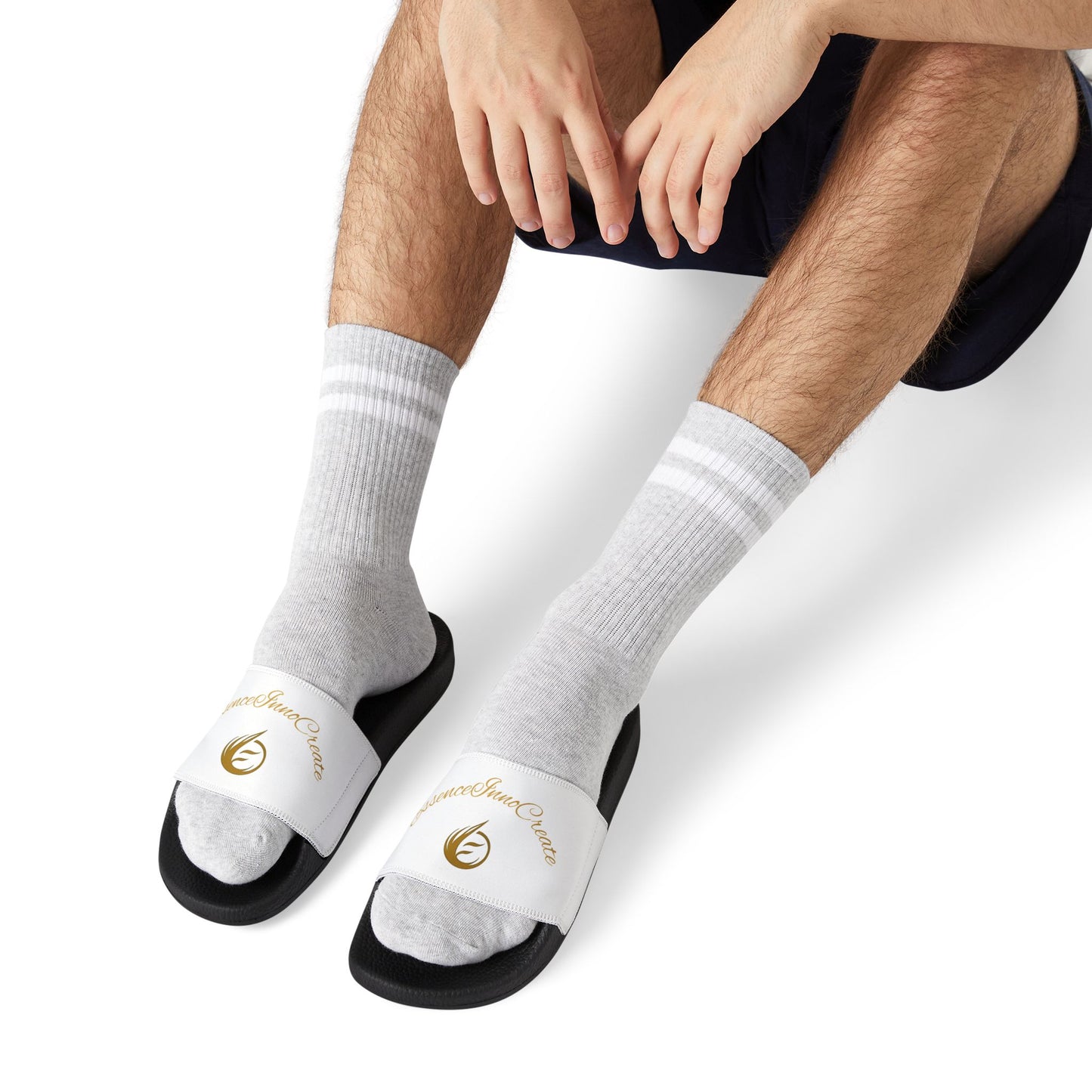 Person wearing white socks with black EssenceInnoCreate slides on a white background